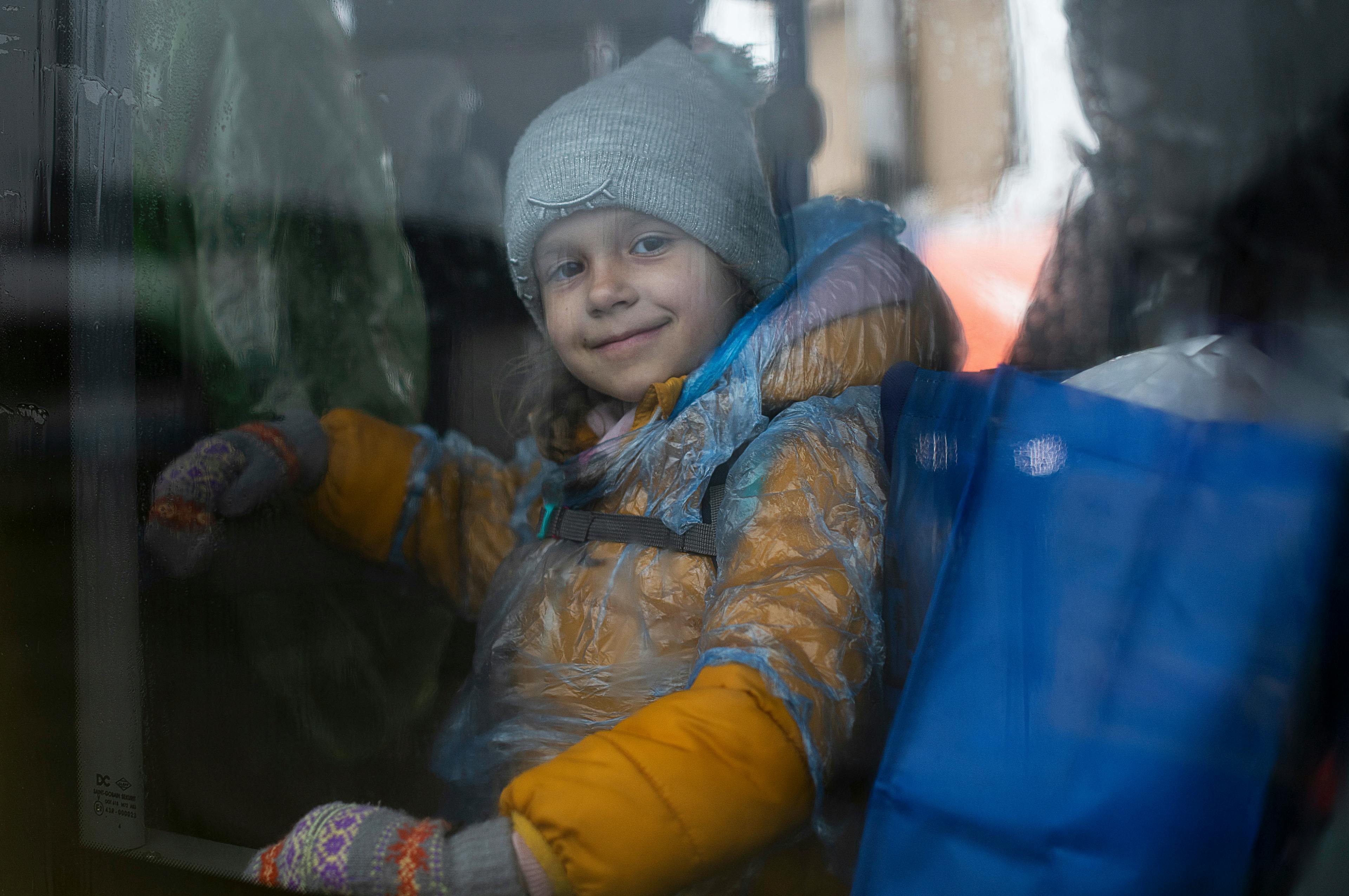 Little girl smiling from a bus in the rain