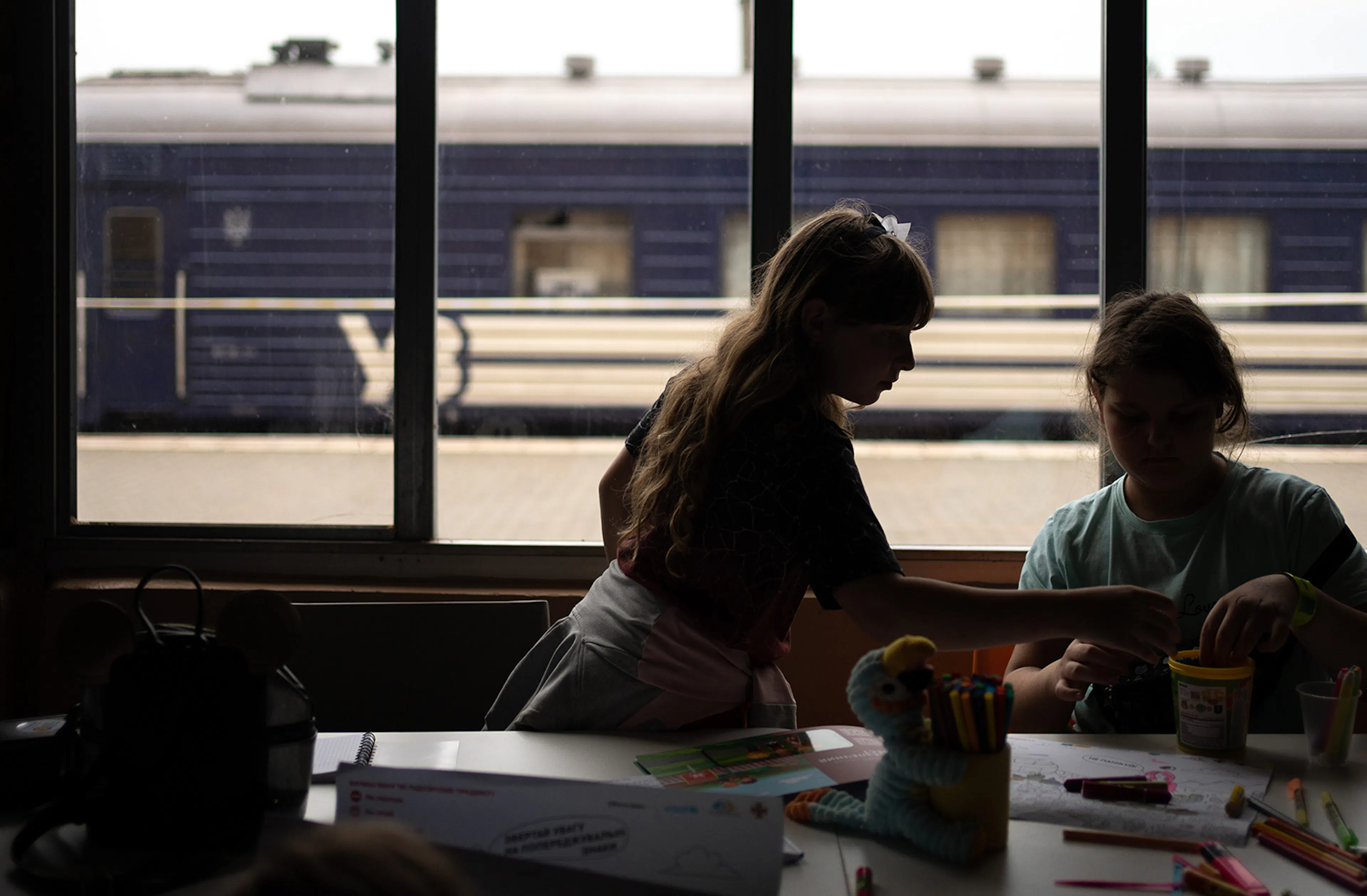 Silhouettes of girls, playing at the Spilno Child Spot at the Mykolaiv railway station. Families fleeing from the shelling and the flood waters flock here. For parents, the Spilno Child Spot is a place where they can find information, get help and have a rest, while for children it is a safe space for playing and communicating.