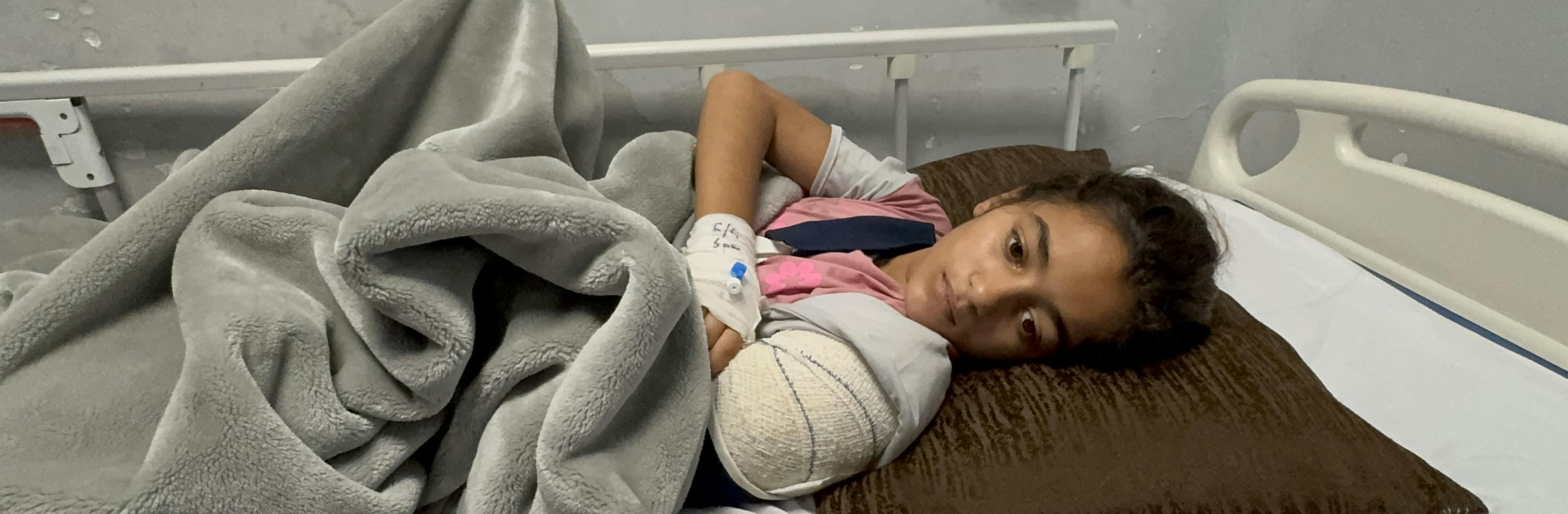 On 7 May 2025, Jana, 10 years old, is photographed lying on a bed at Nasser Hospital in the Gaza Strip, recovering from a serious arm injury.

