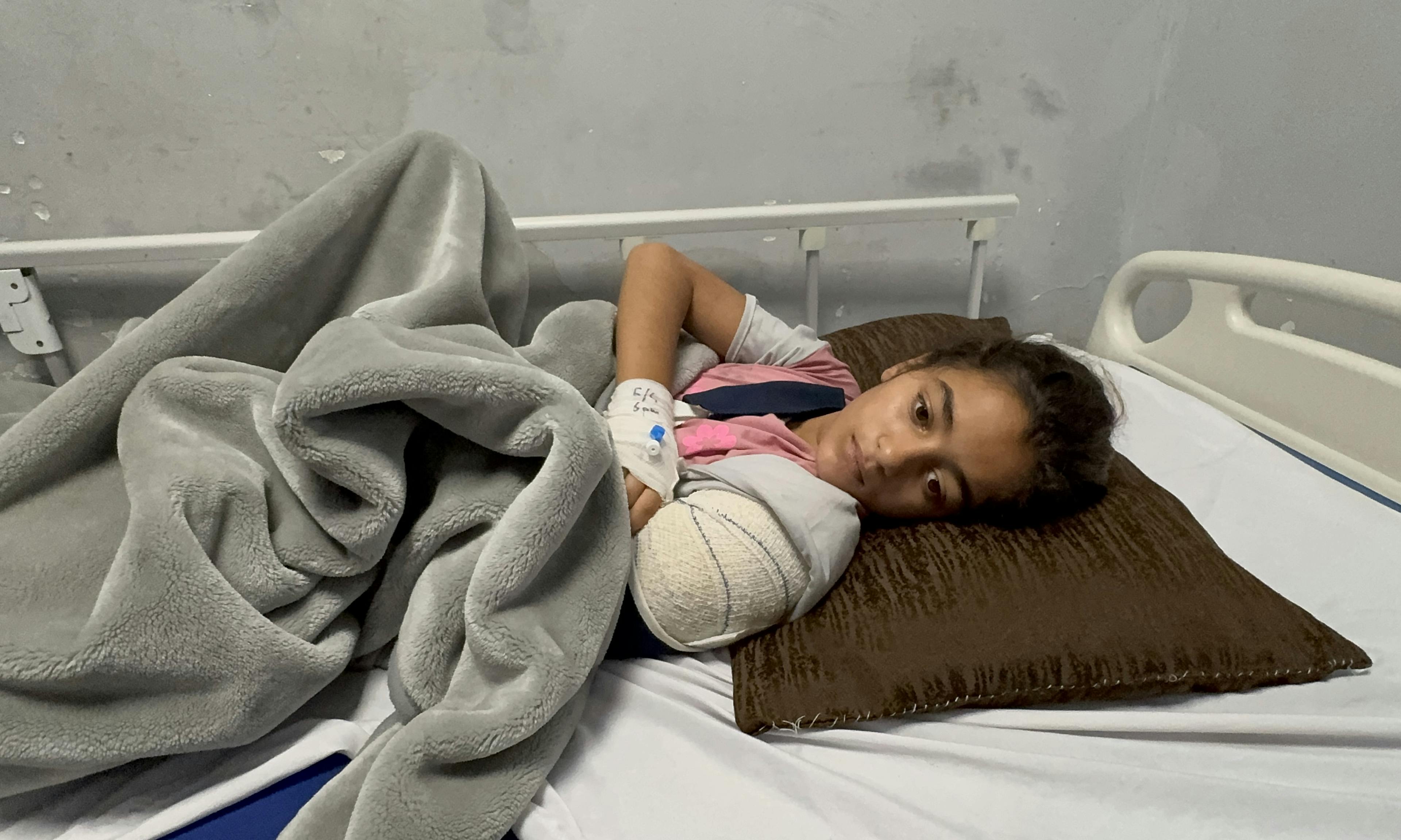 On 7 May 2025, Jana, 10 years old, is photographed lying on a bed at Nasser Hospital in the Gaza Strip, recovering from a serious arm injury.

