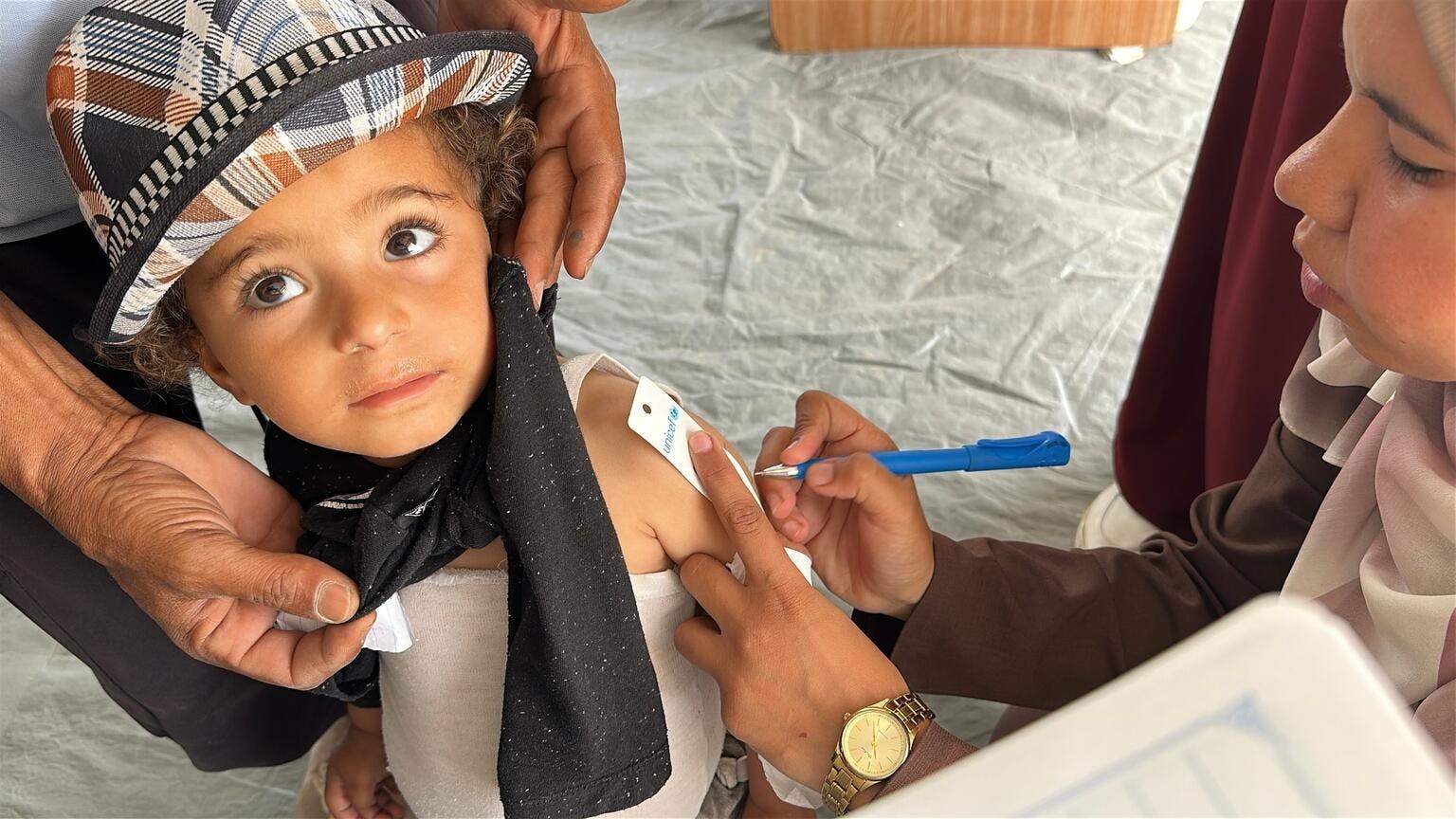 On 7 May 2025, at the UNICEF-supported nutrition clinic in Al Farooq Camp, Khan Yunis, a child is screened for malnutrition using a MUAC (mid-upper-arm circumference) band.