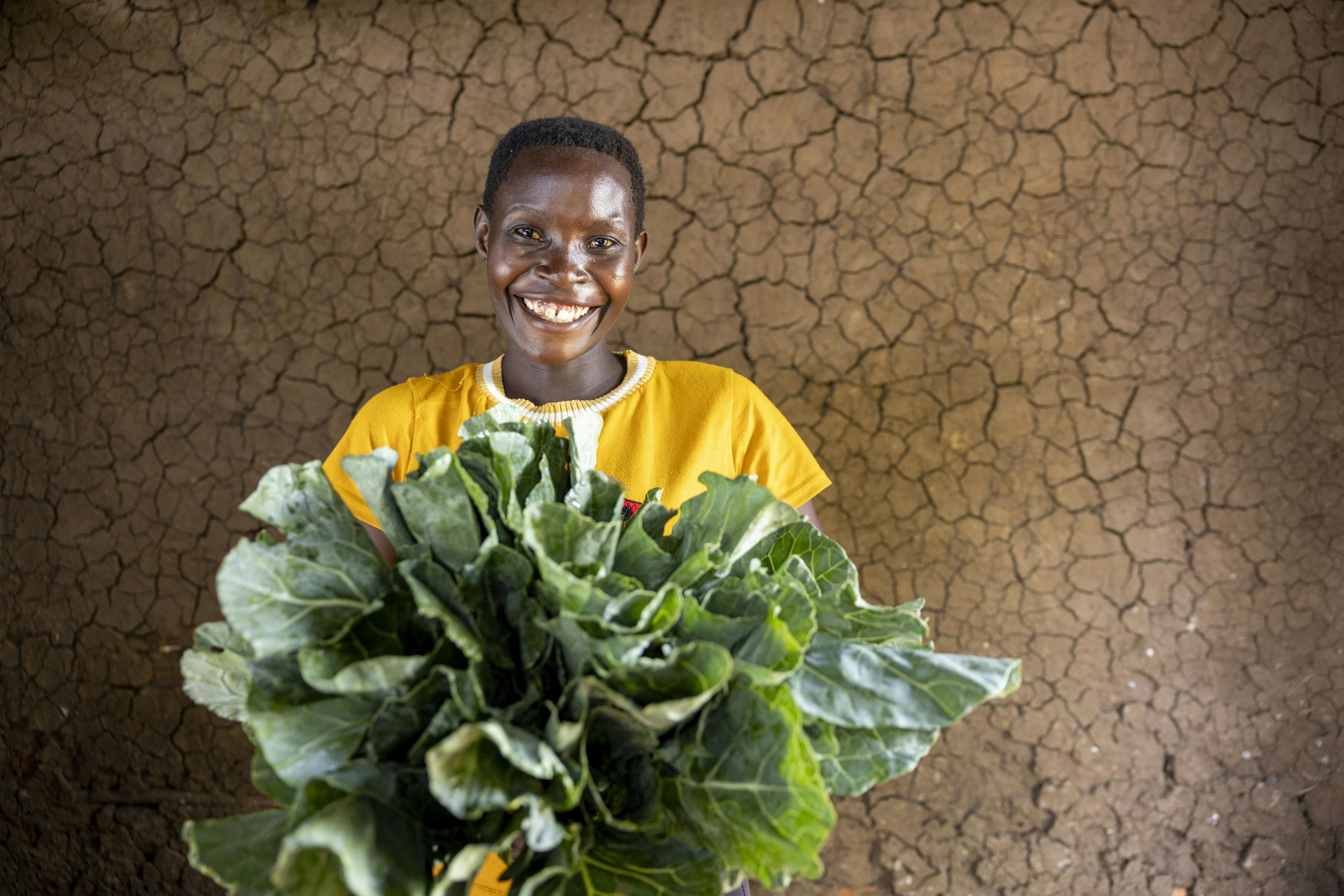 24-year-old Jackline Nabwire shows off her rich harvest from her sukuma wiki garden, Bukwanja Village, Buswale Sub-county, Namayingo District, 6 May 2025.