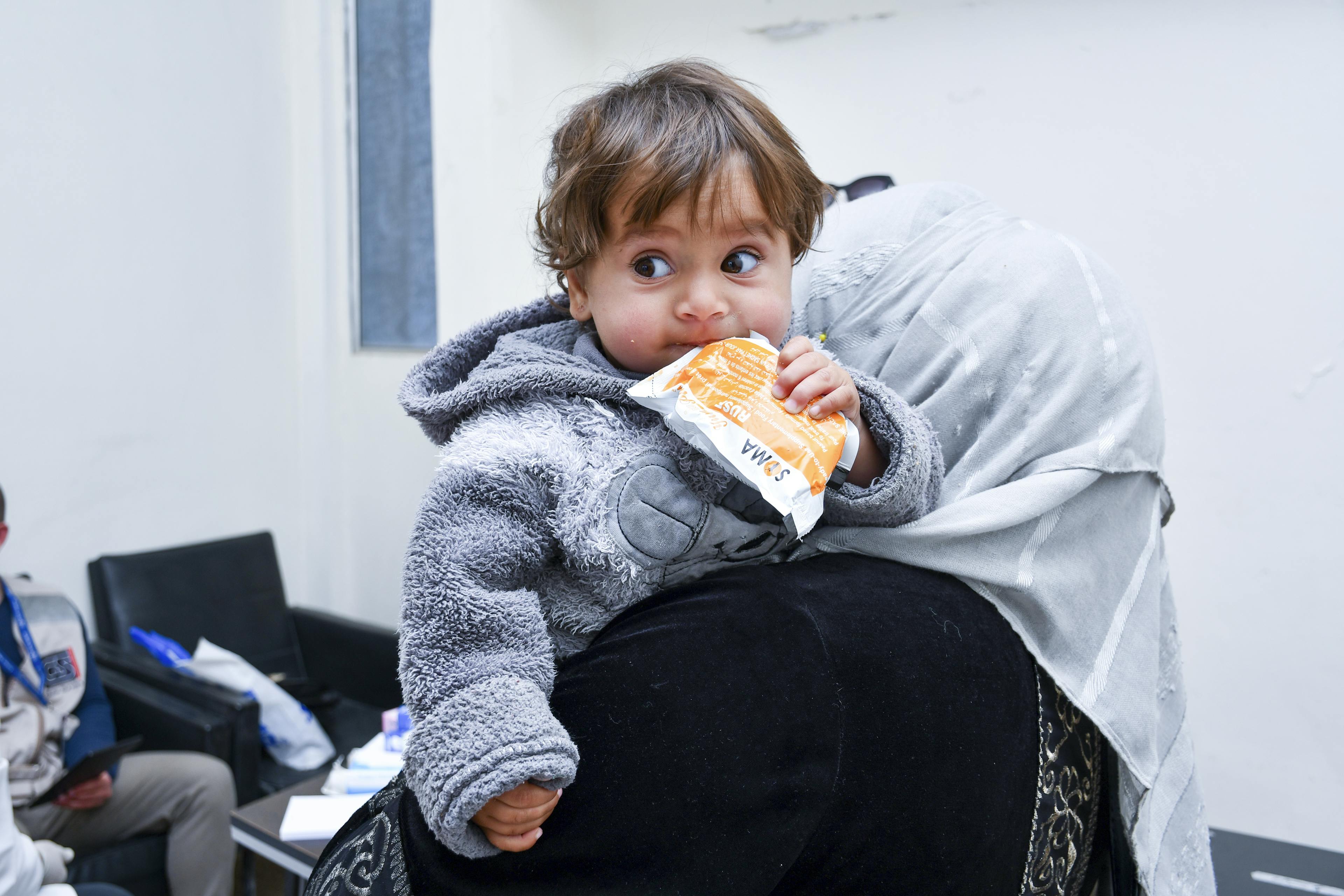 Ten-month-old Raghad holds therapeutic food as her mother receives guidance from a UNICEF-supported mobile team in Rural Damascus, on 17 March 2025.
