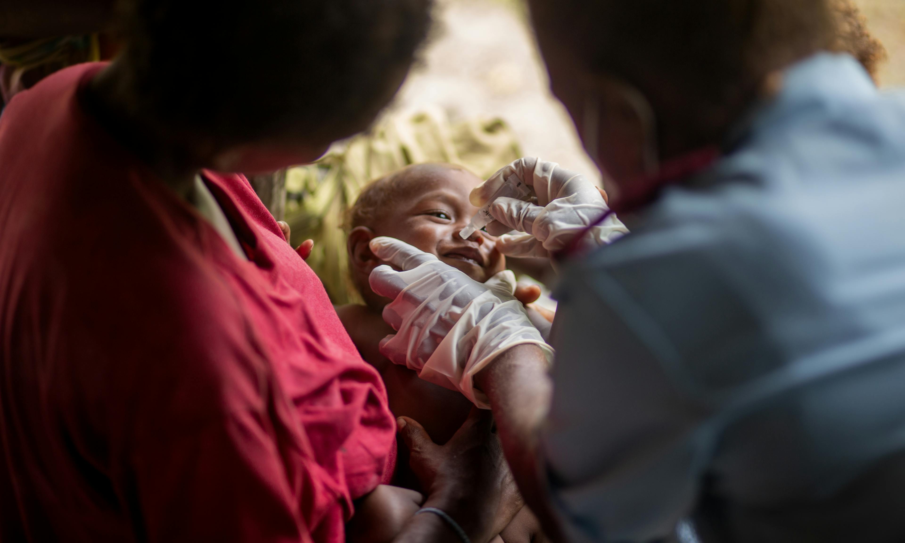 Peter is comforted by his mother, Senovevo, while Nurse Rosemary Raikekeni provides him a dose of rotavirus vaccine in Kuvamiti, East Guadalcanal, Solomon Islands, on 17 May 2023.