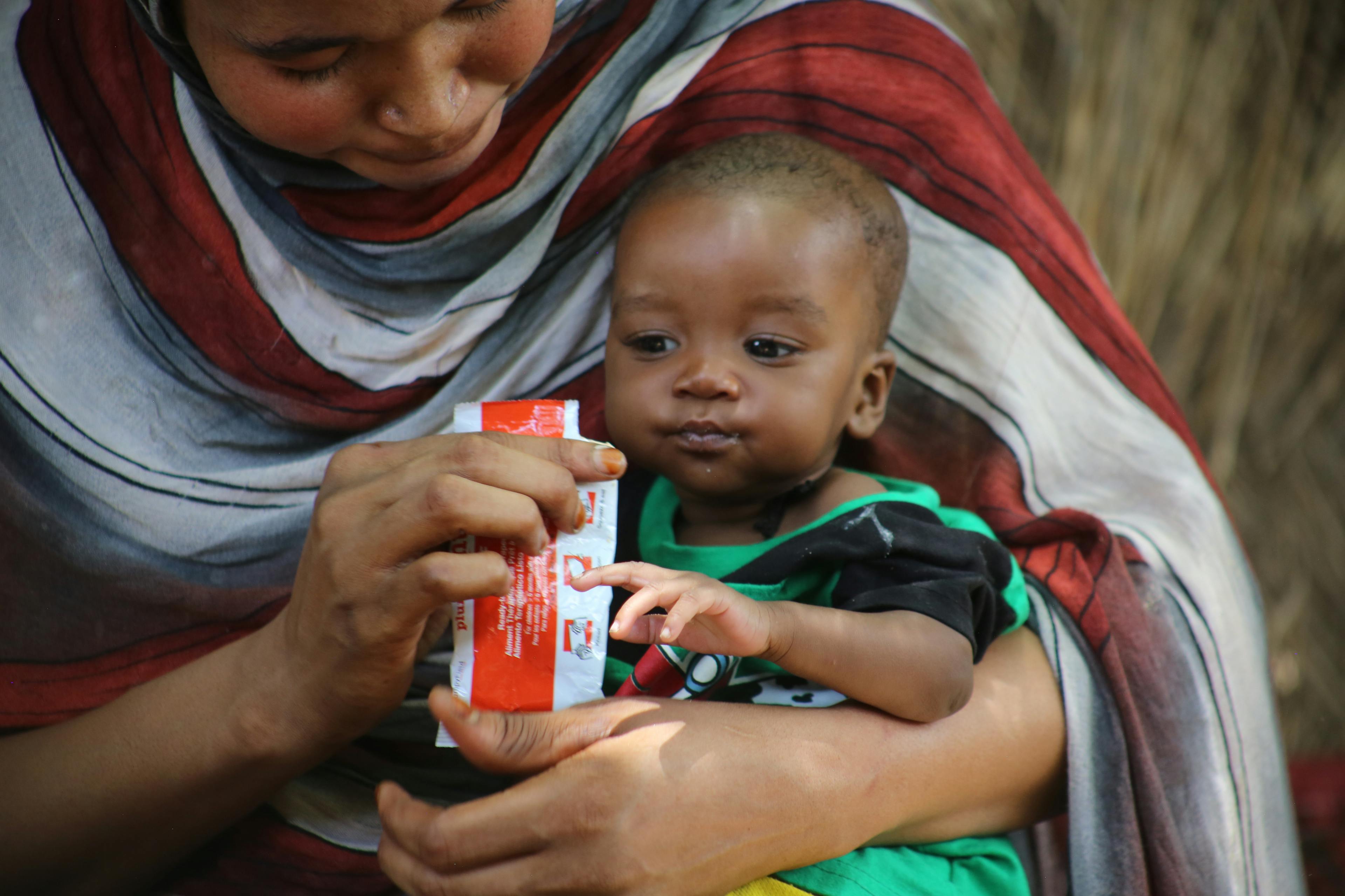 On 1 May 2024, mother Manahil feeds her 6-month-old child, Baraa, ready-to-use-therapeutic food (RUTF) at their home in Damazine, Blue Nile state, Sudan. Baraa is recovering from severe acute malnutrition and is enrolled in a UNICEF-supported nutrition programme for care and treatment.