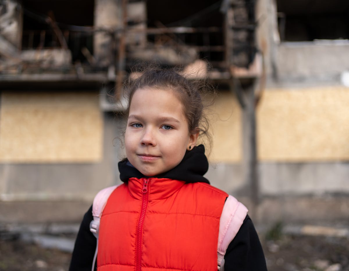 Eight-year-old Myroslava stands in front of a bombed-out residential building, one of several damaged in a missile strike on 7 March 2025.