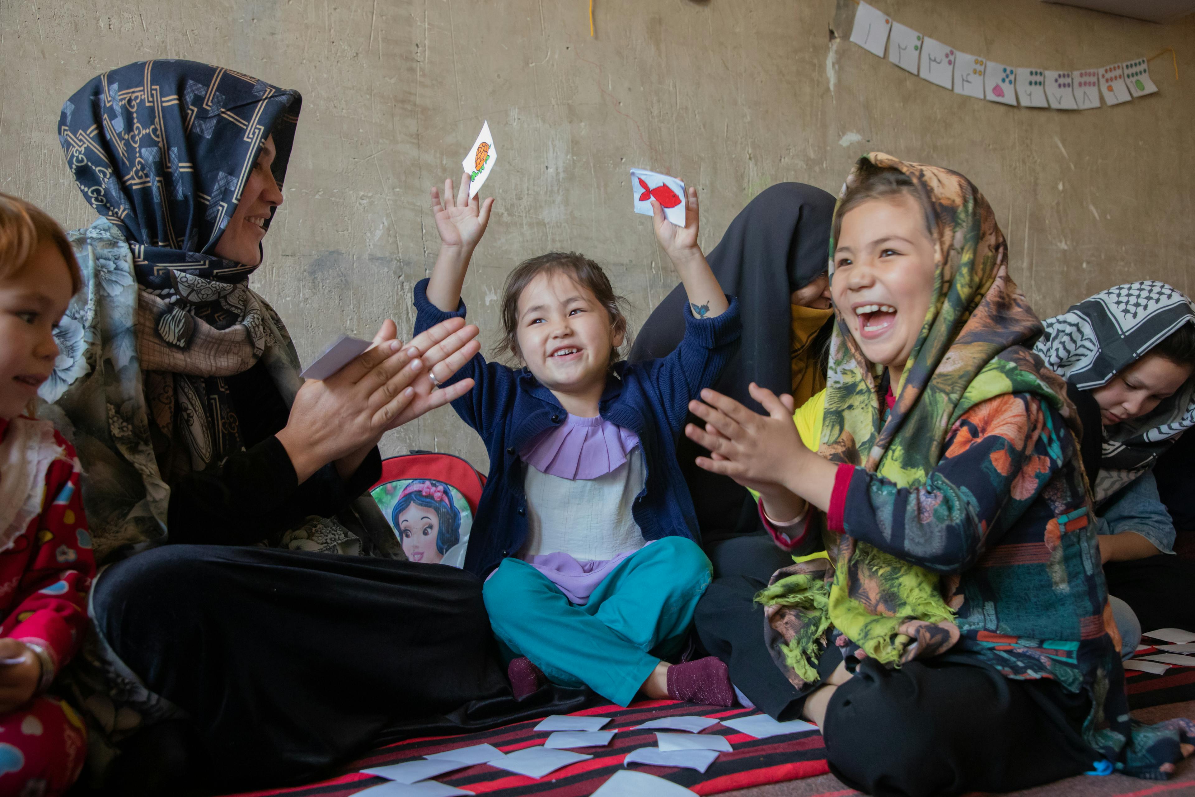 Nargis, 5 and Zahra 8 years old playing with cards with their mother Hamidah