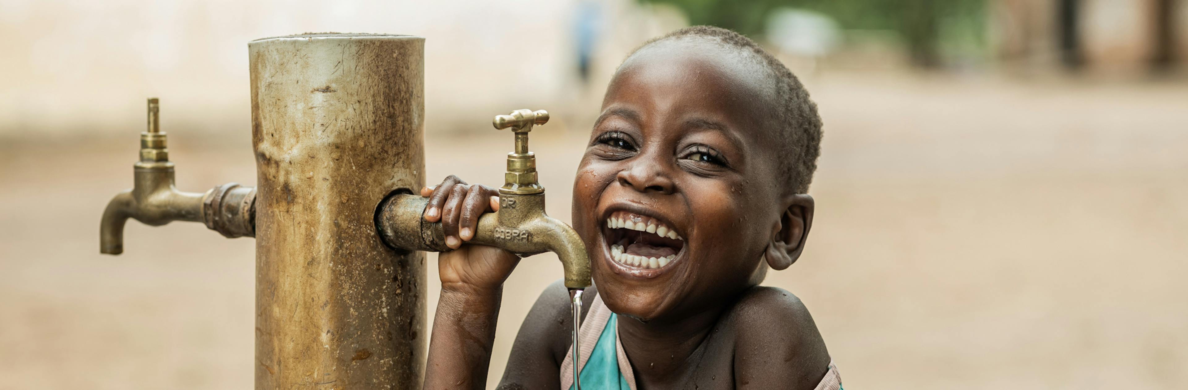 4 year old  Owen Kayinga drinking water from a UNICEF donated water tap.
