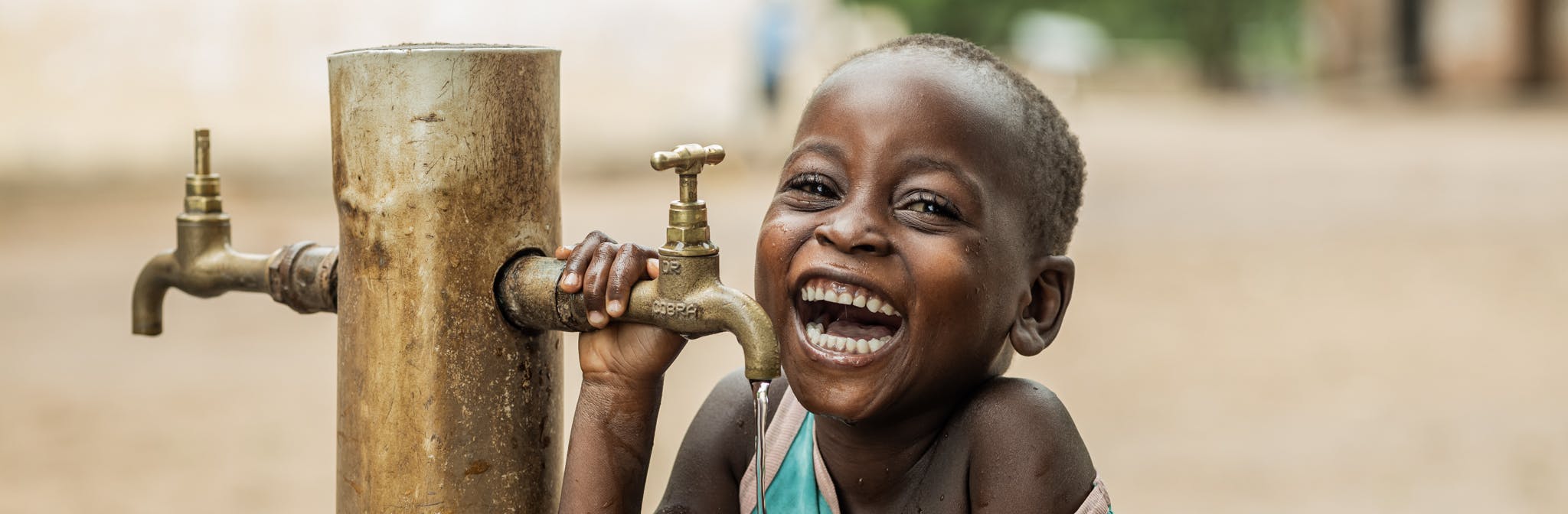 4 year old Owen Kayinga drinking water from a UNICEF donated water tap.
