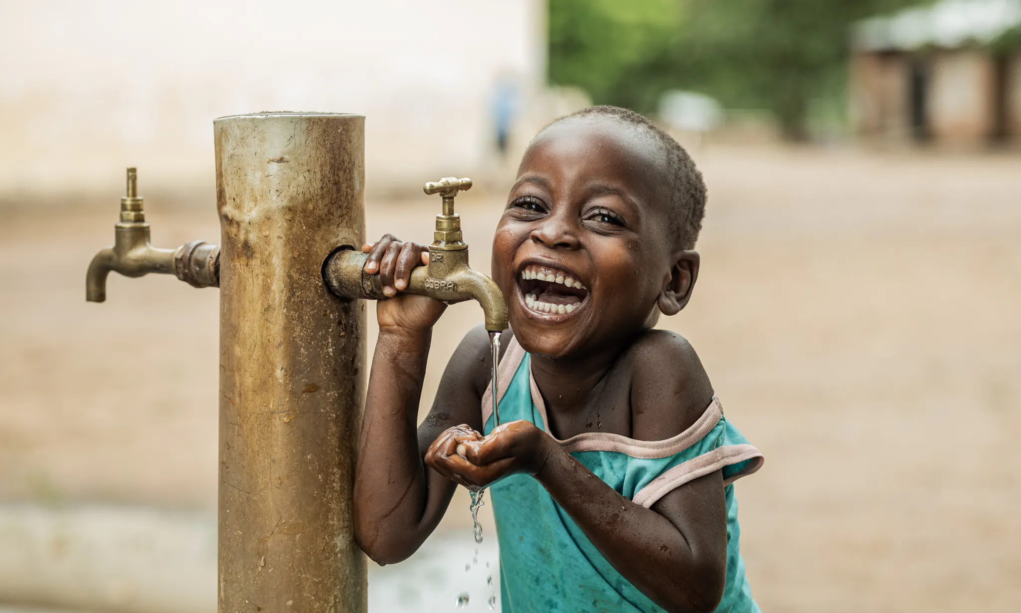 4 year old Owen Kayinga drinking water from a UNICEF donated water tap.