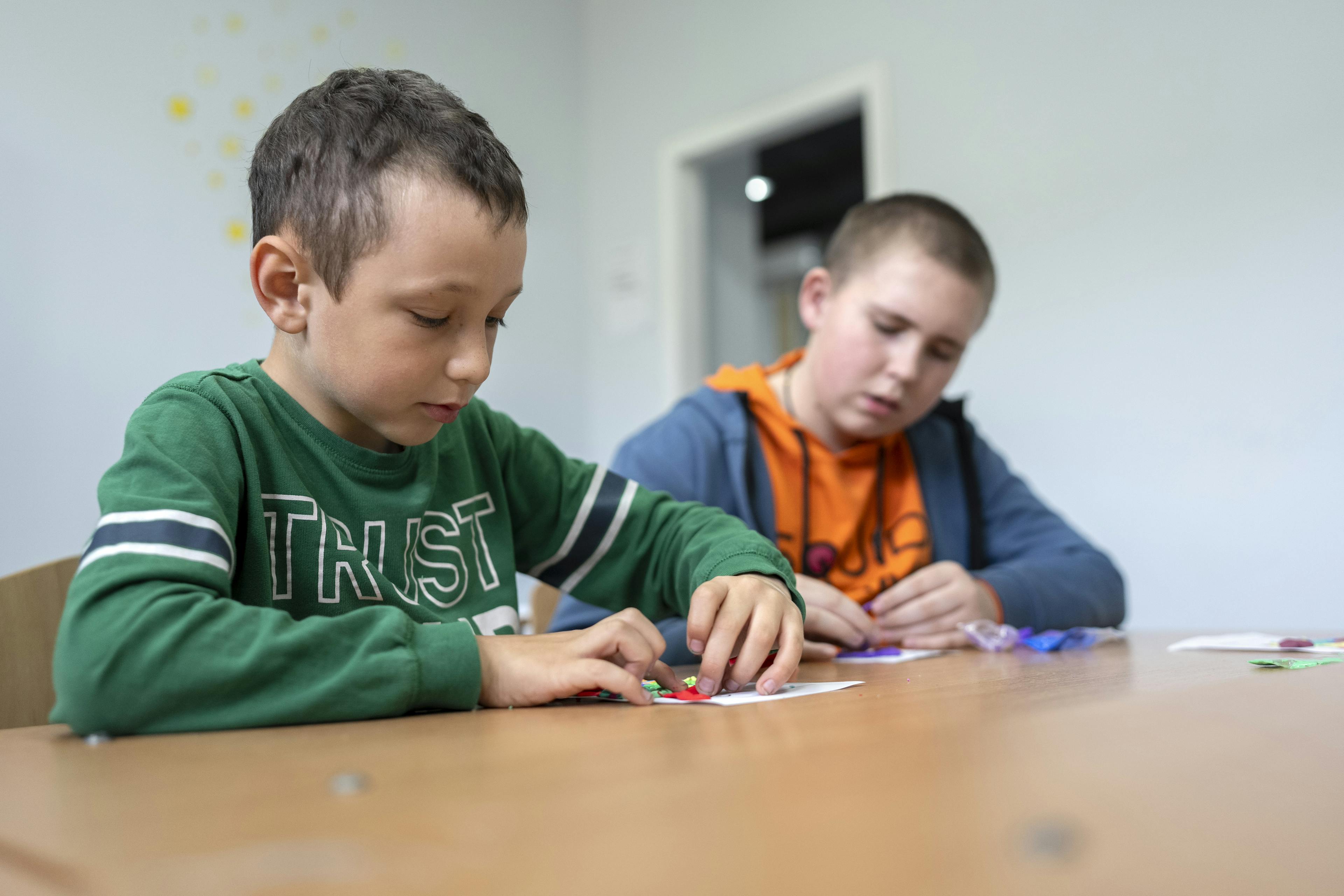 Seven-year-old Vitya (left) concentrates on an art project during a creative session at the UNICEF-supported Safe Space in Izium.