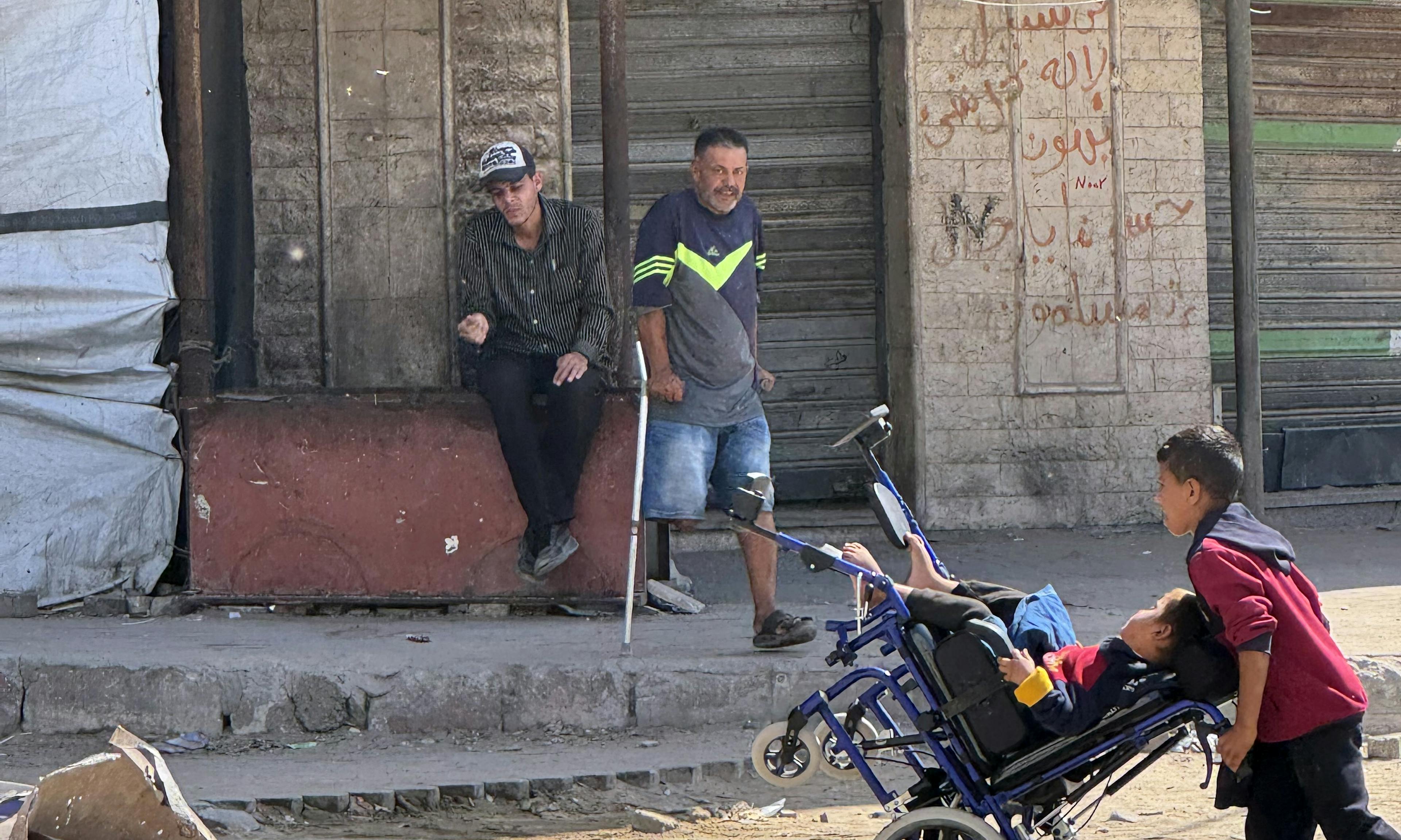 A child pushes another child in a wheelchair through the streets of Gaza City in the Gaza Strip on 2 October 2025.

