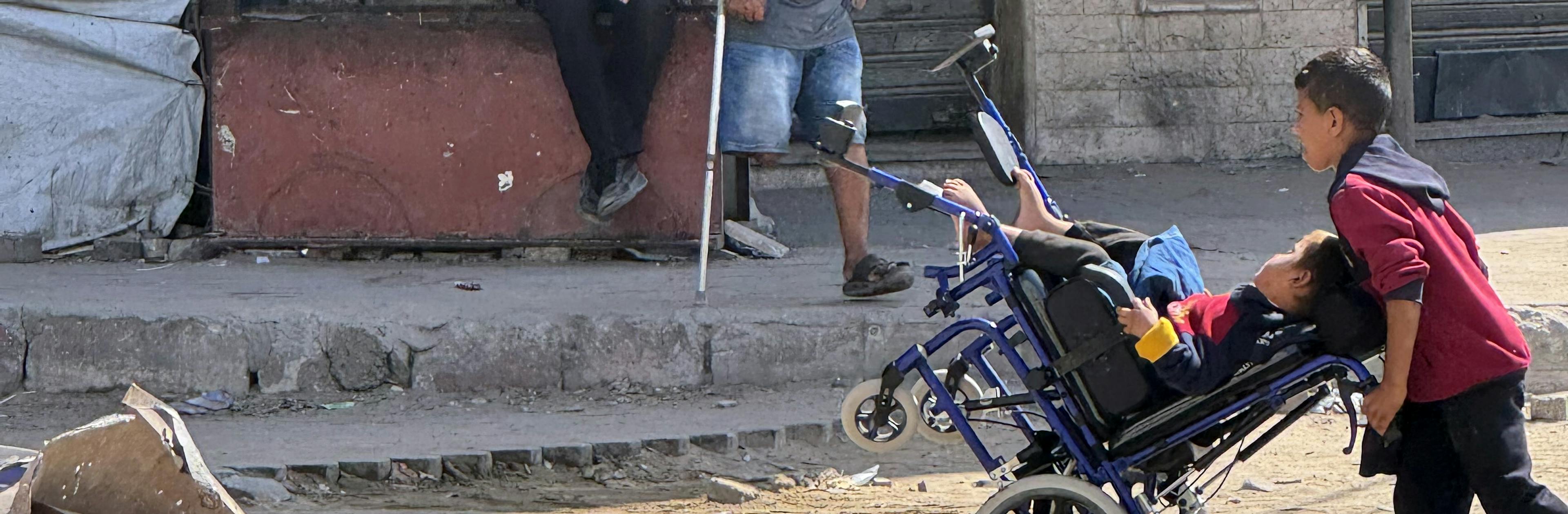 A child pushes another child in a wheelchair through the streets of Gaza City in the Gaza Strip on 2 October 2025.

