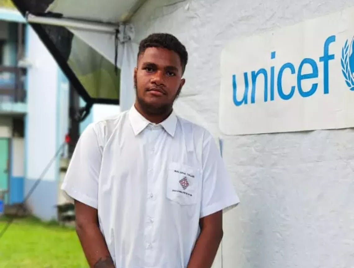 A Vanuatu teenager stands by a UNICEF sign