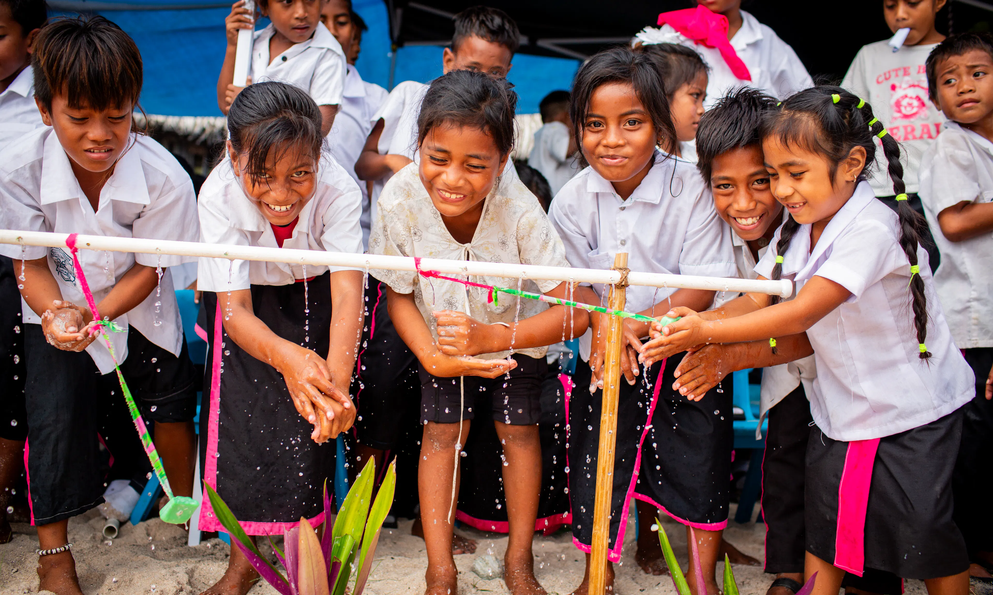 Children washing their hands using a tippy tap