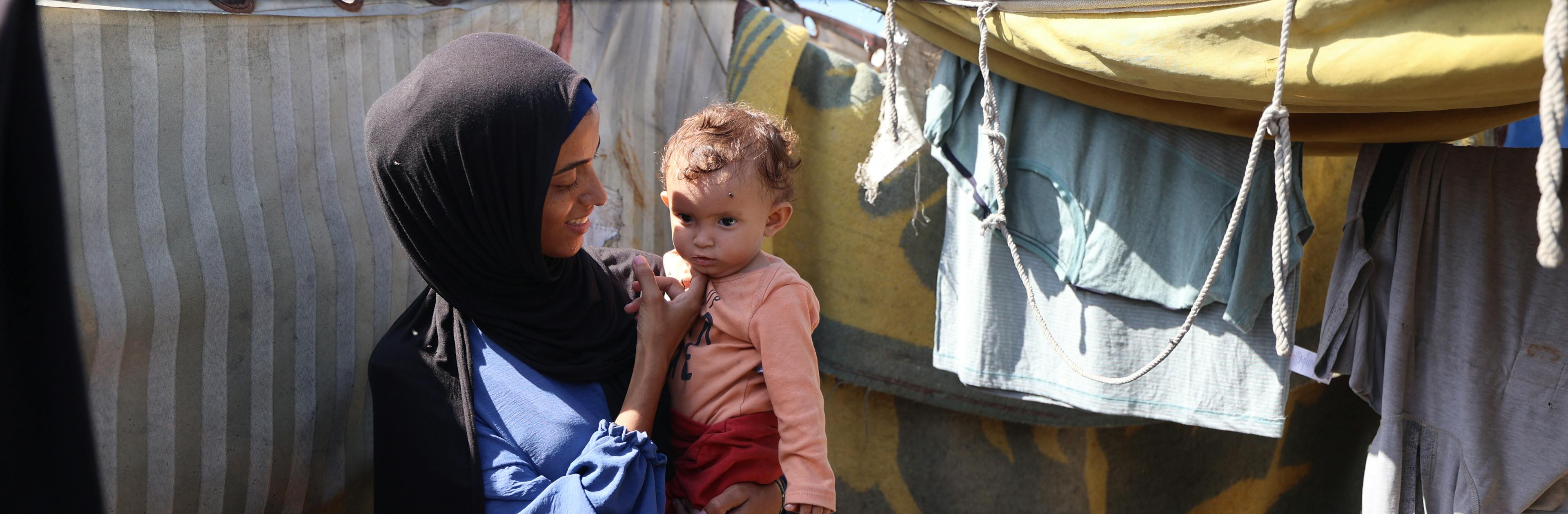 Rania holds her daughter Lareen outside their makeshift tent in Al-Mawasi in the Gaza strip.