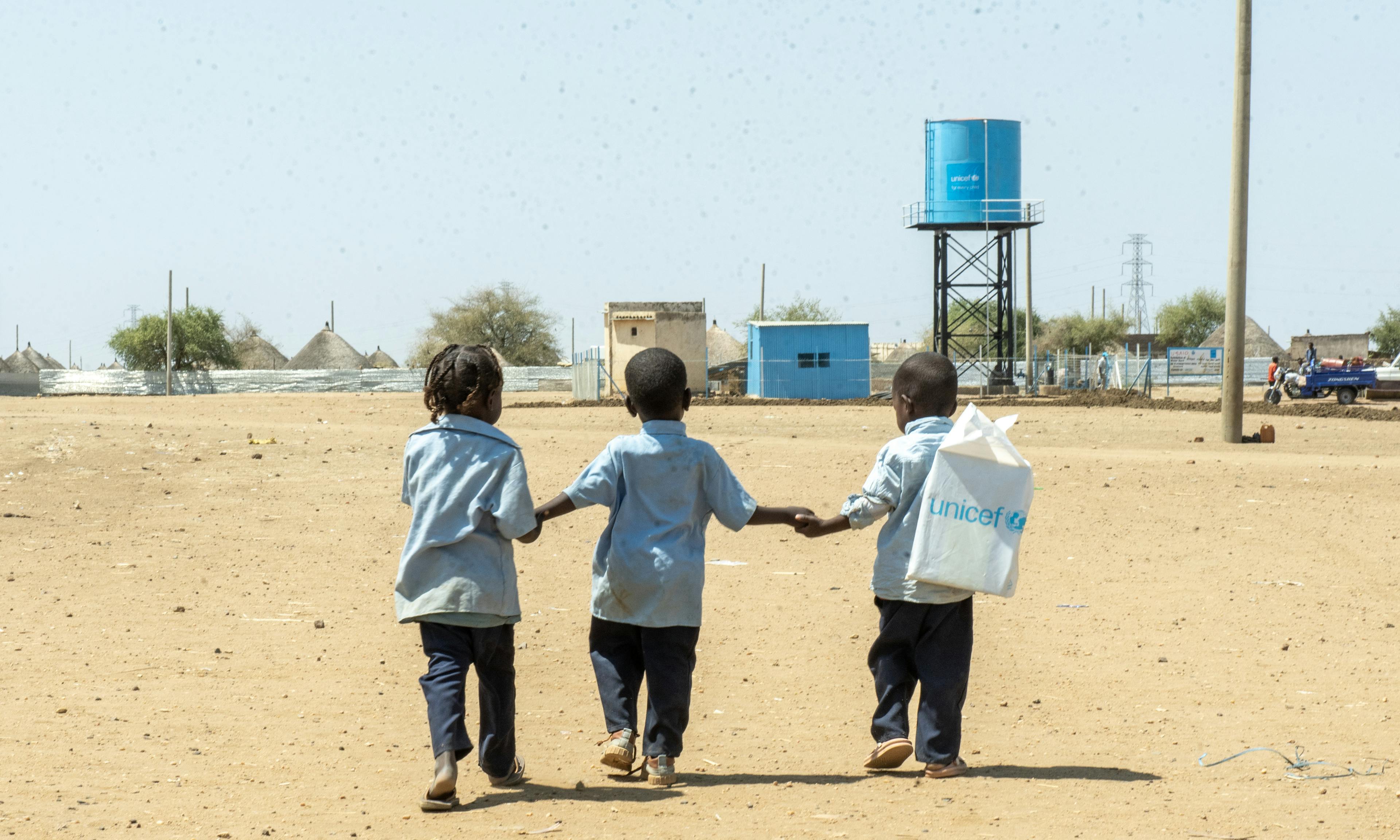 Three Children Hold Hands in Rural Sudan
