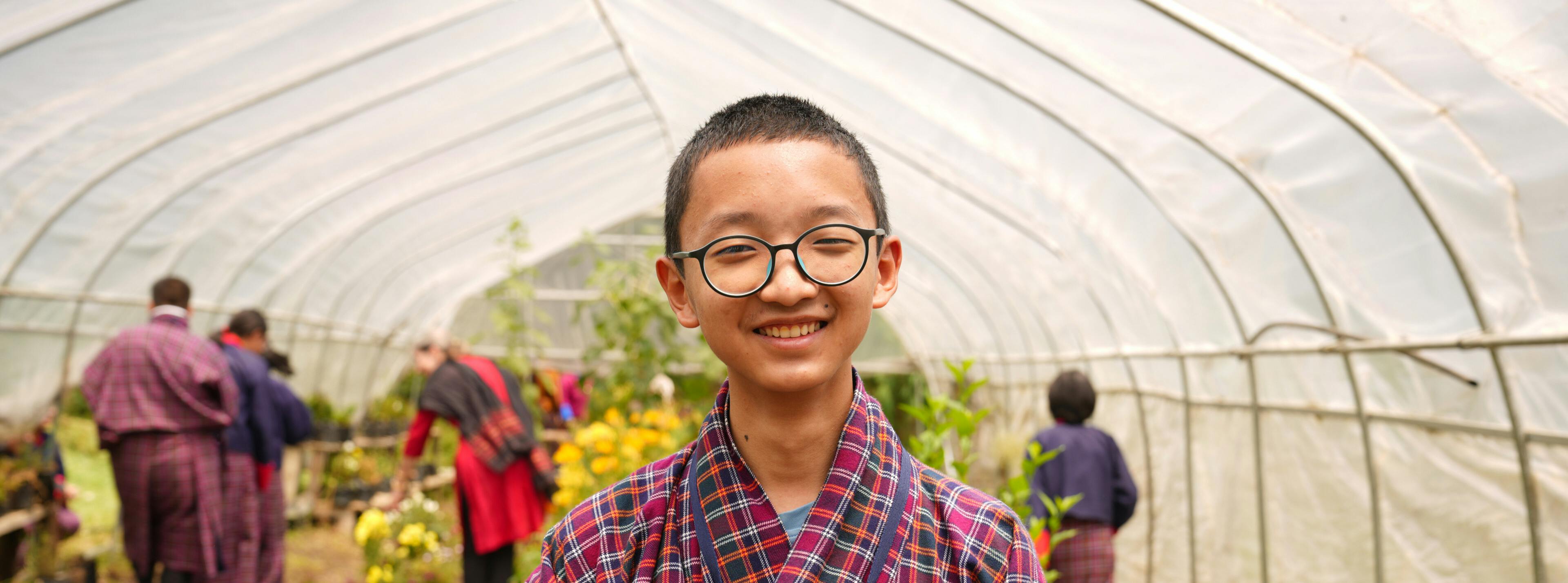 A Bhutan student smiling in a greenhouse
