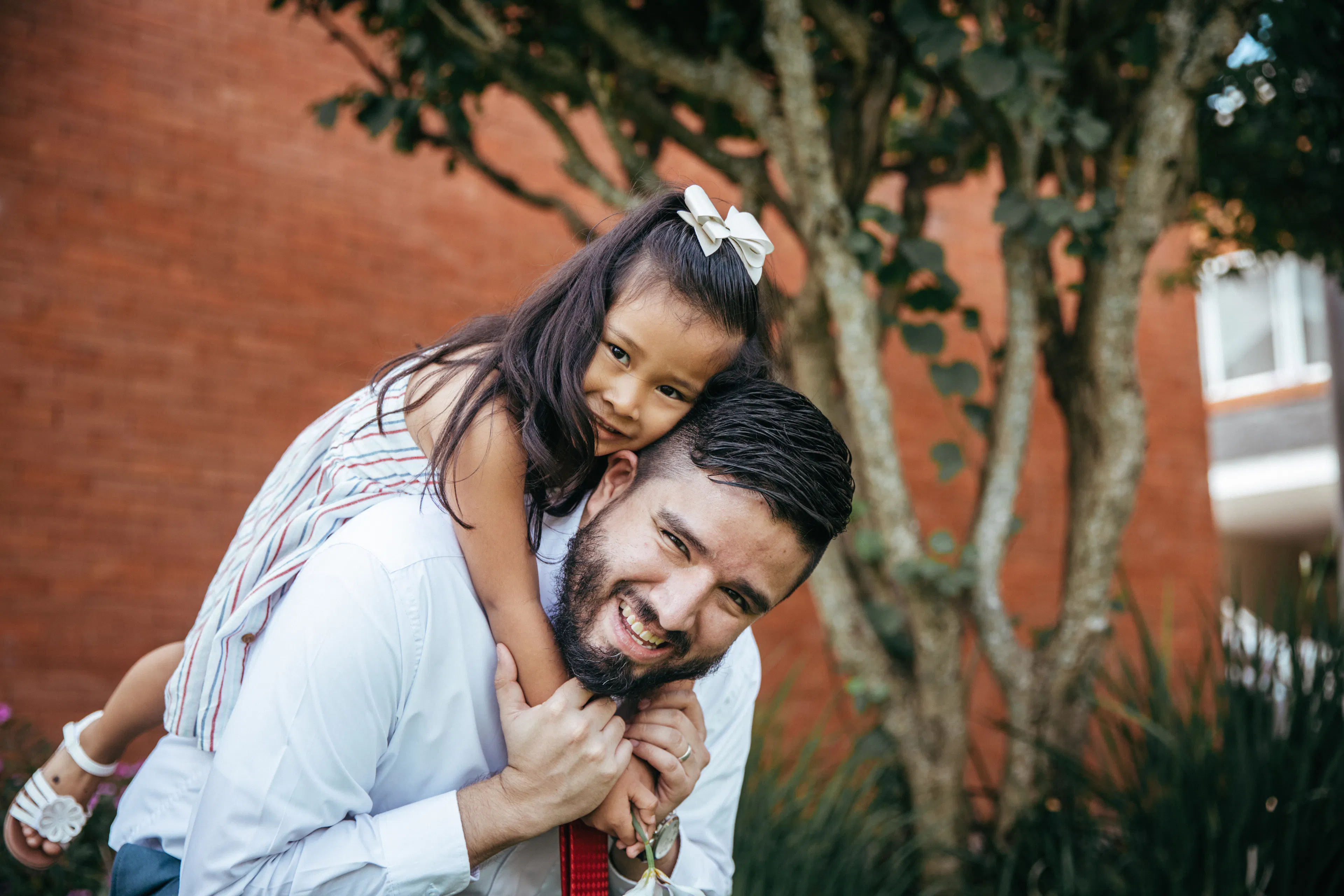 Father and daughter smile together and father lifts daughter up