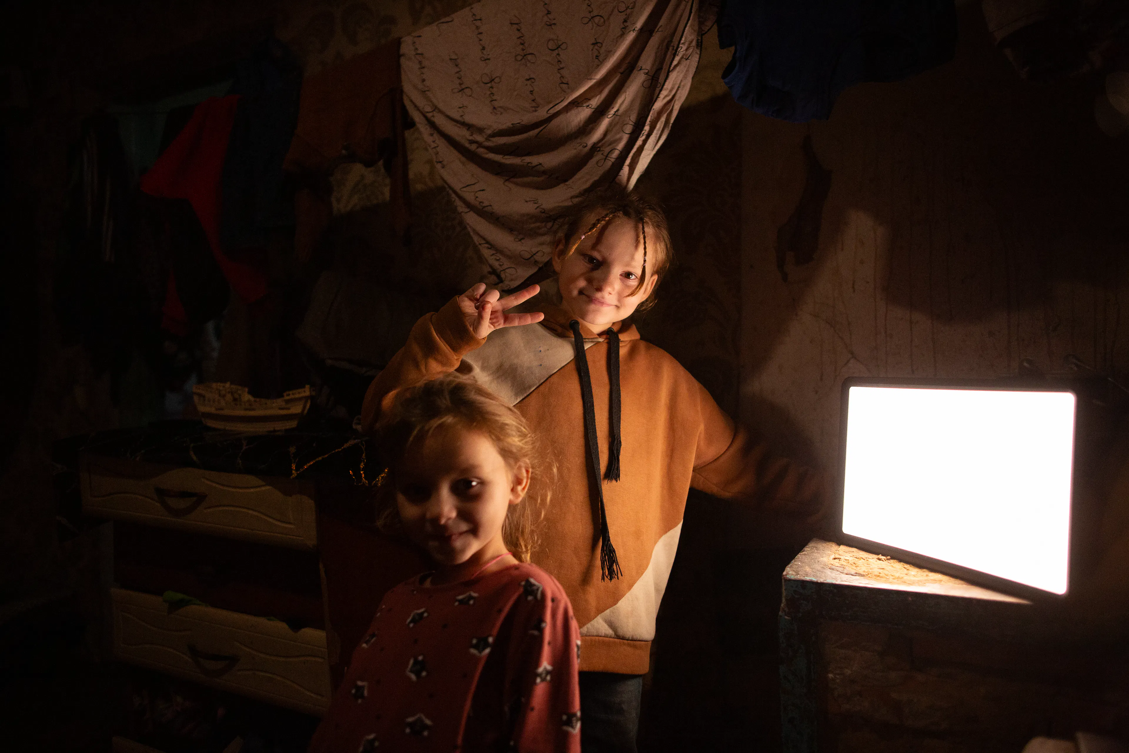 Two girls smile by a light at night time in Ukraine during conflict