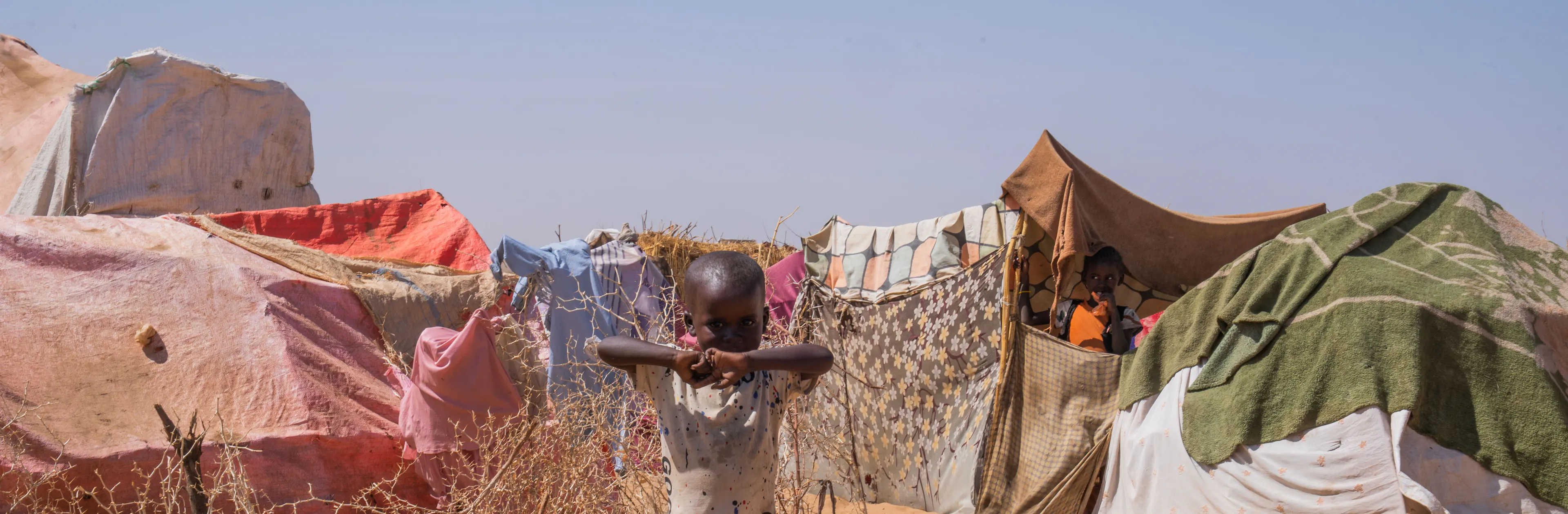 Child-in-Sudan-stands-among-tents-amid-conflict