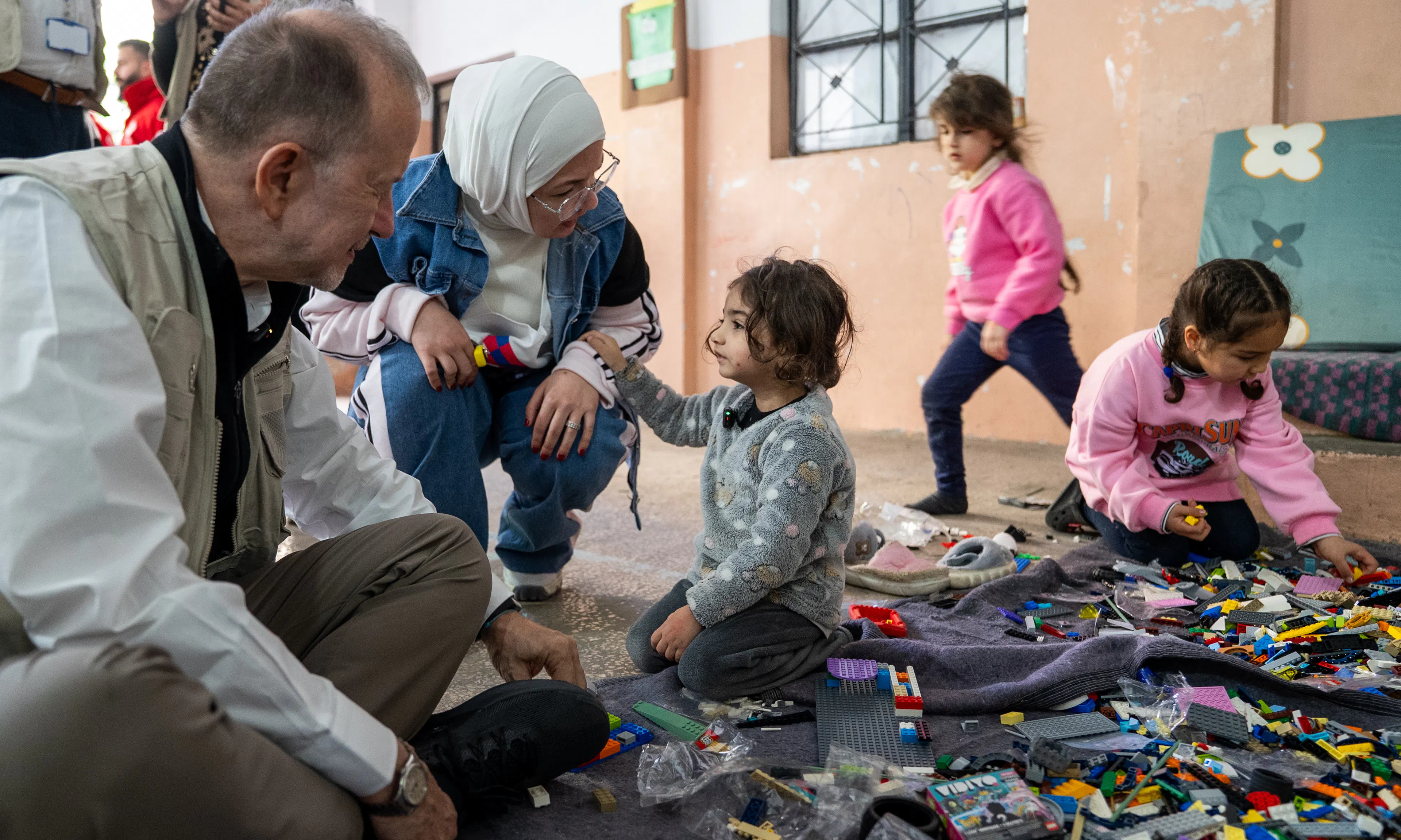 On 17 March 2026 in Lebanon, Ted Chaiban, UNICEF Deputy Executive Director for Humanitarian Action and Supply Operations, sits and interacts with 3-year-old Narjes (centre) while meeting displaced children and families sheltering at the Omar Faroukh school in Beirut.