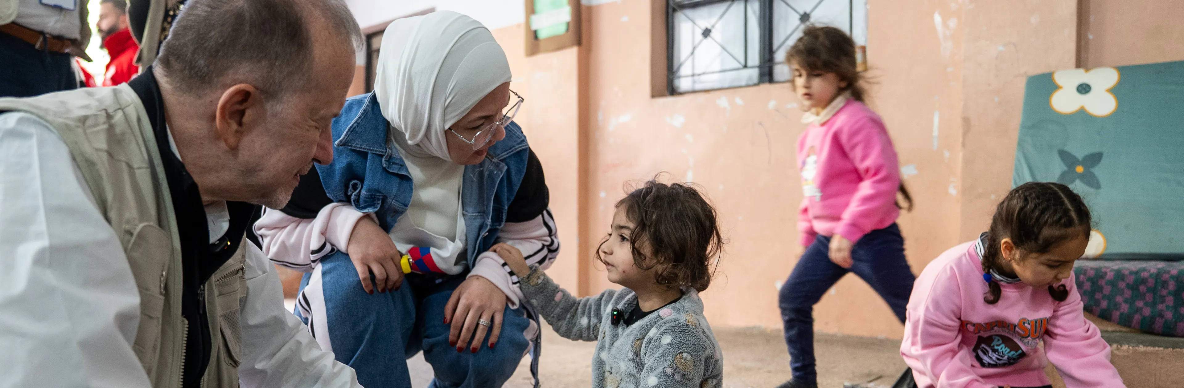 On 17 March 2026 in Lebanon, Ted Chaiban, UNICEF Deputy Executive Director for Humanitarian Action and Supply Operations, sits and interacts with 3-year-old Narjes (centre) while meeting displaced children and families sheltering at the Omar Faroukh school in Beirut.