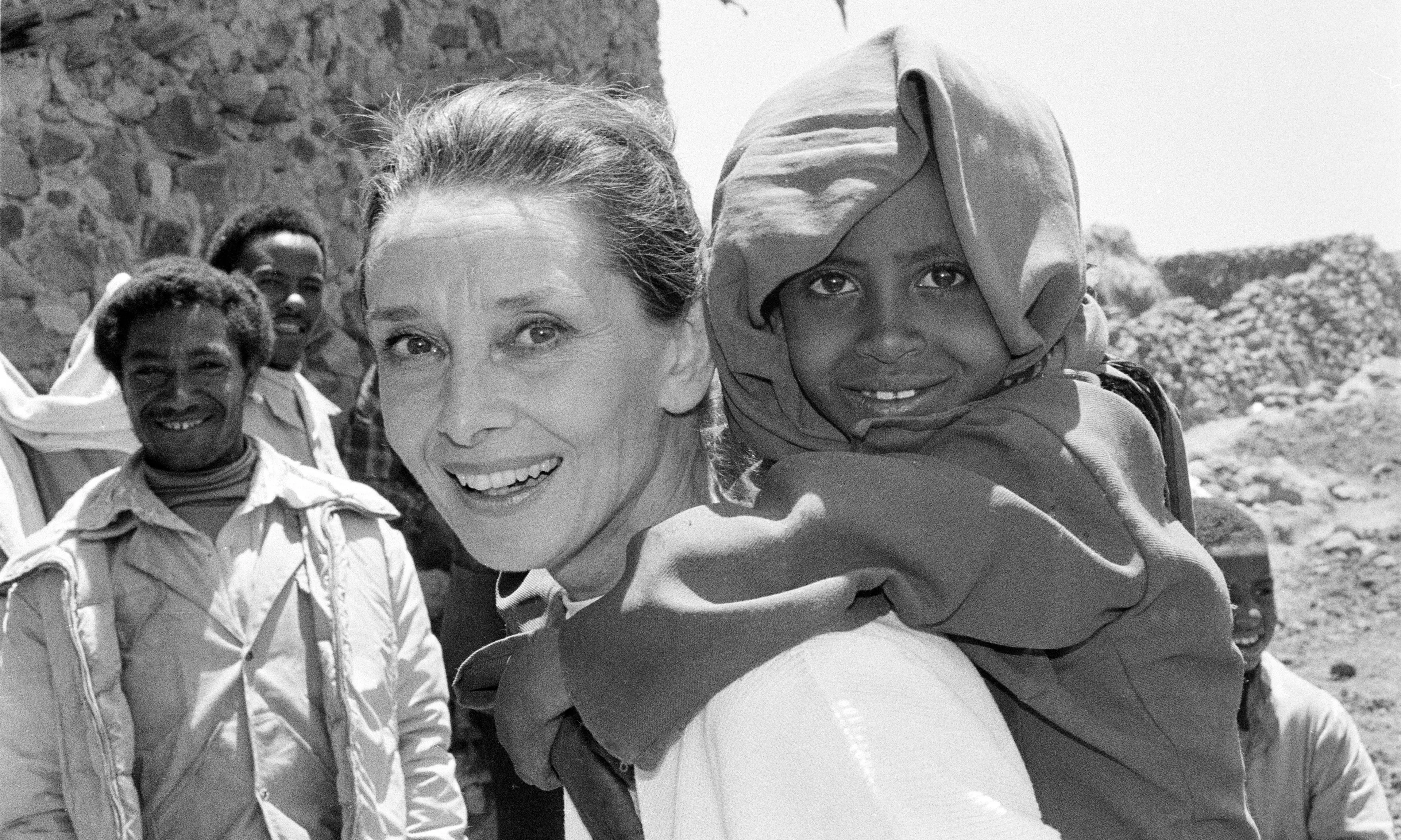 UNICEF Goodwill Ambassador Audrey Hepburn smiles as she carries a child on her back, in the northern town of Mehal Meda in Shoa Province. Ms. Hepburn was visiting a food distribution centre in the town.