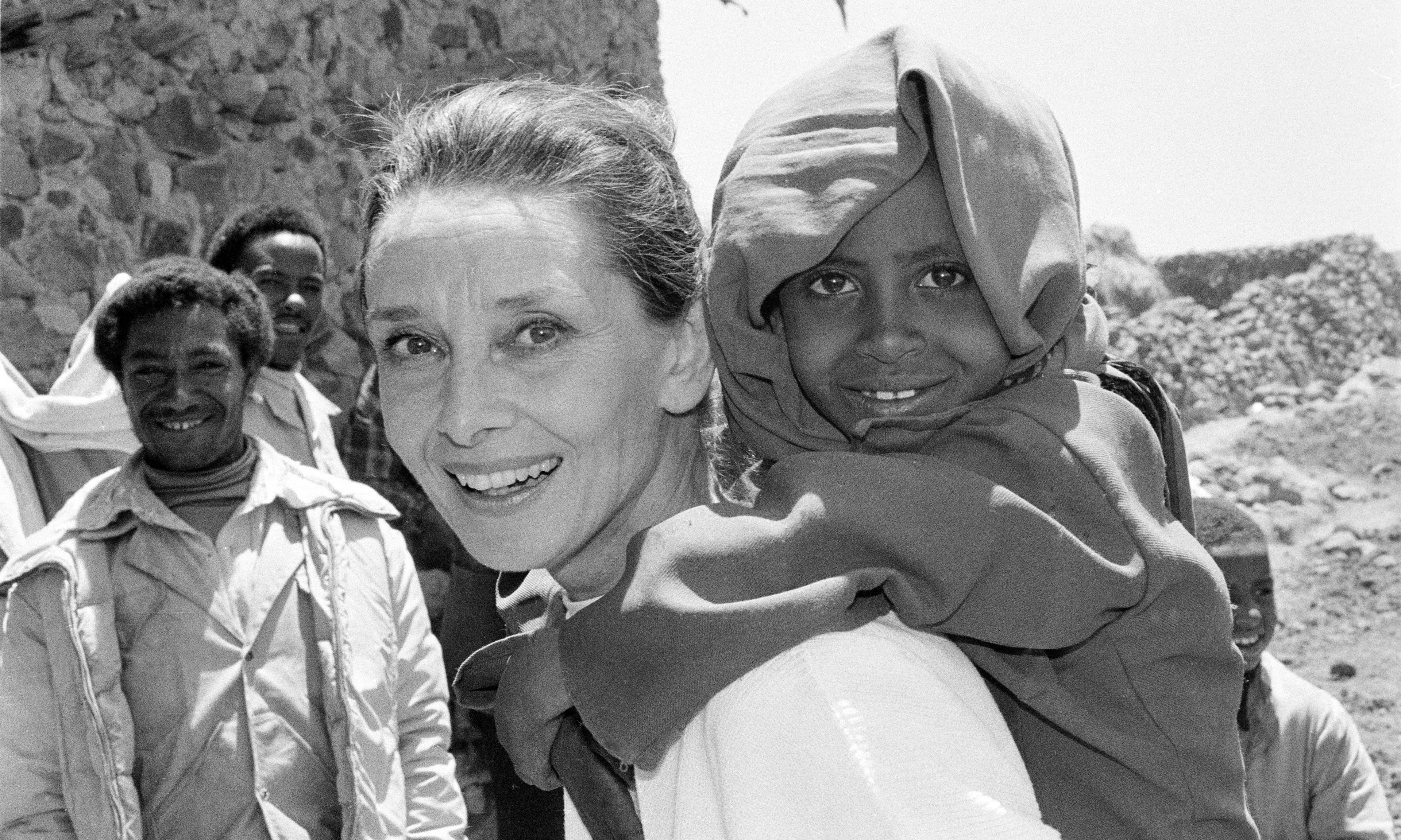 UNICEF Goodwill Ambassador Audrey Hepburn smiles as she carries a child on her back, in the northern town of Mehal Meda in Shoa Province. Ms. Hepburn was visiting a food distribution centre in the town.