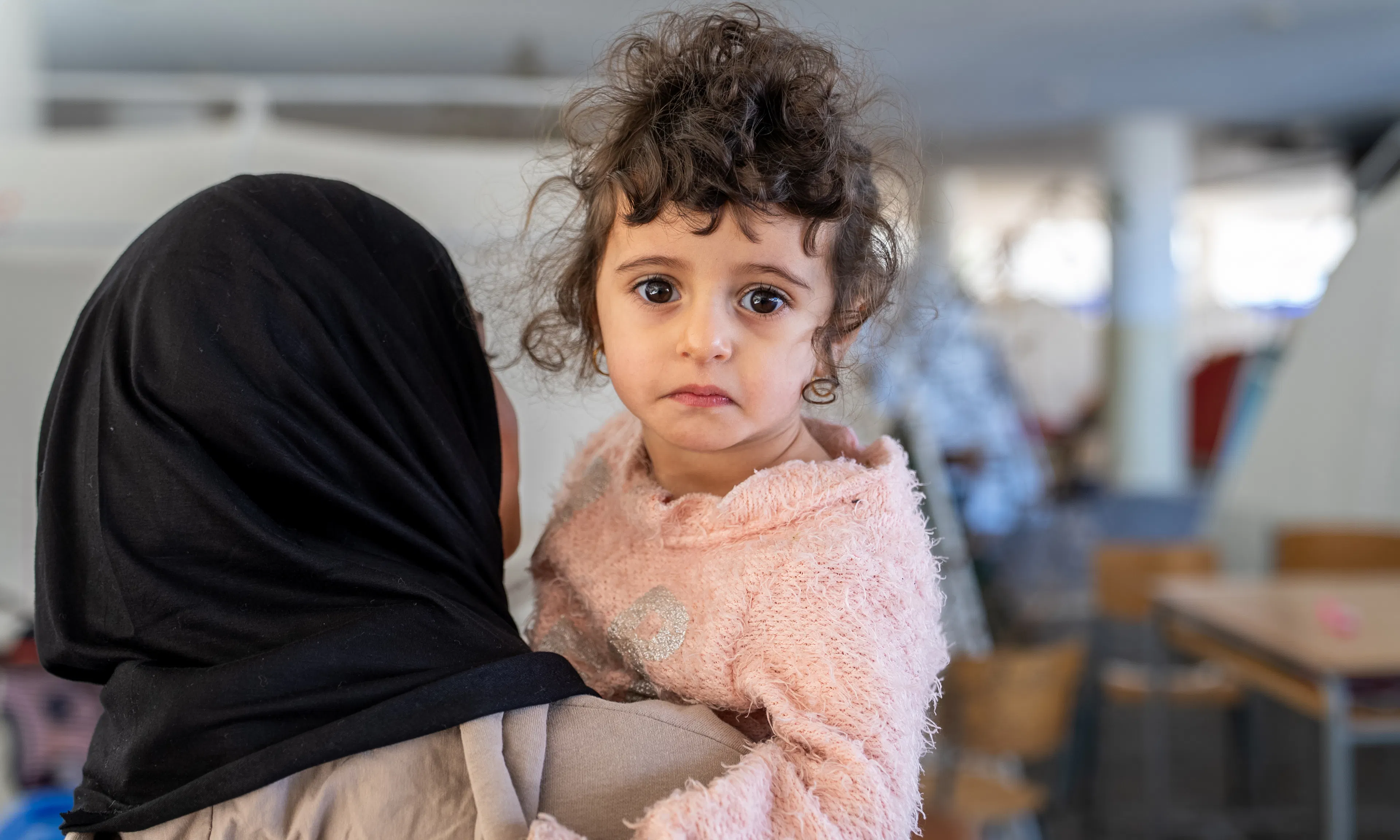 On 17 March 2026 in Lebanon, 2-year old Fatima is held by Fadak, 12, at Omar Faroukh school in Beirut, where hundreds of internally displaced people are currently staying after fleeing violence.