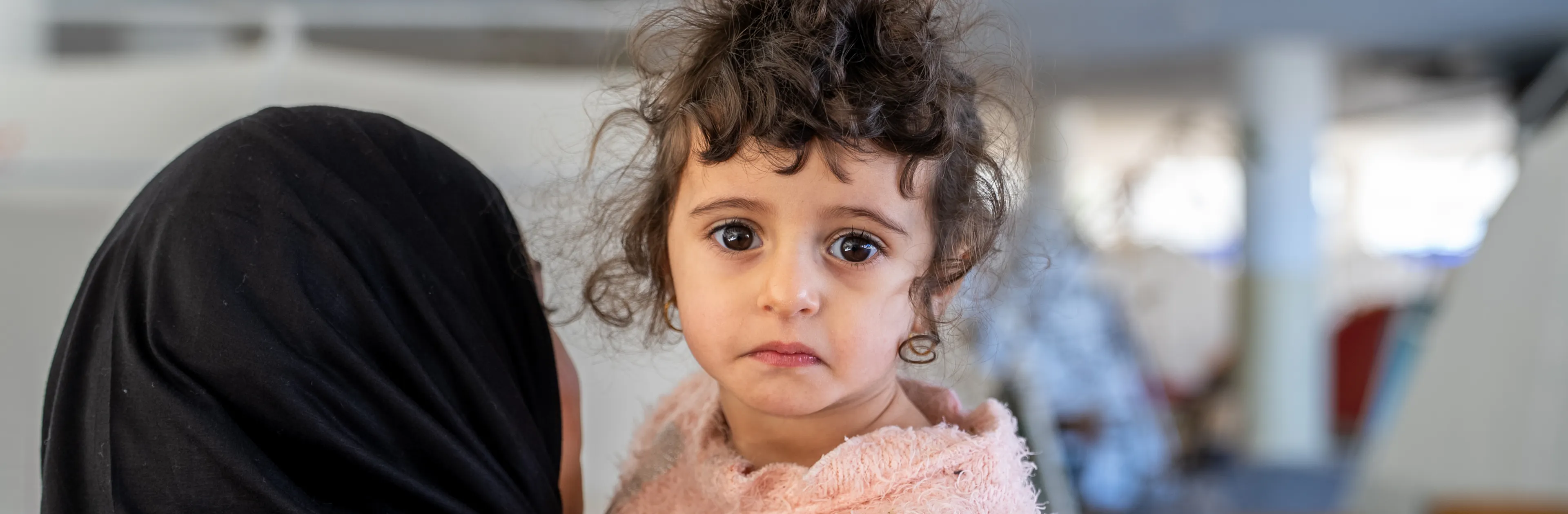 On 17 March 2026 in Lebanon, 2-year old Fatima is held by Fadak, 12, at Omar Faroukh school in Beirut, where hundreds of internally displaced people are currently staying after fleeing violence.