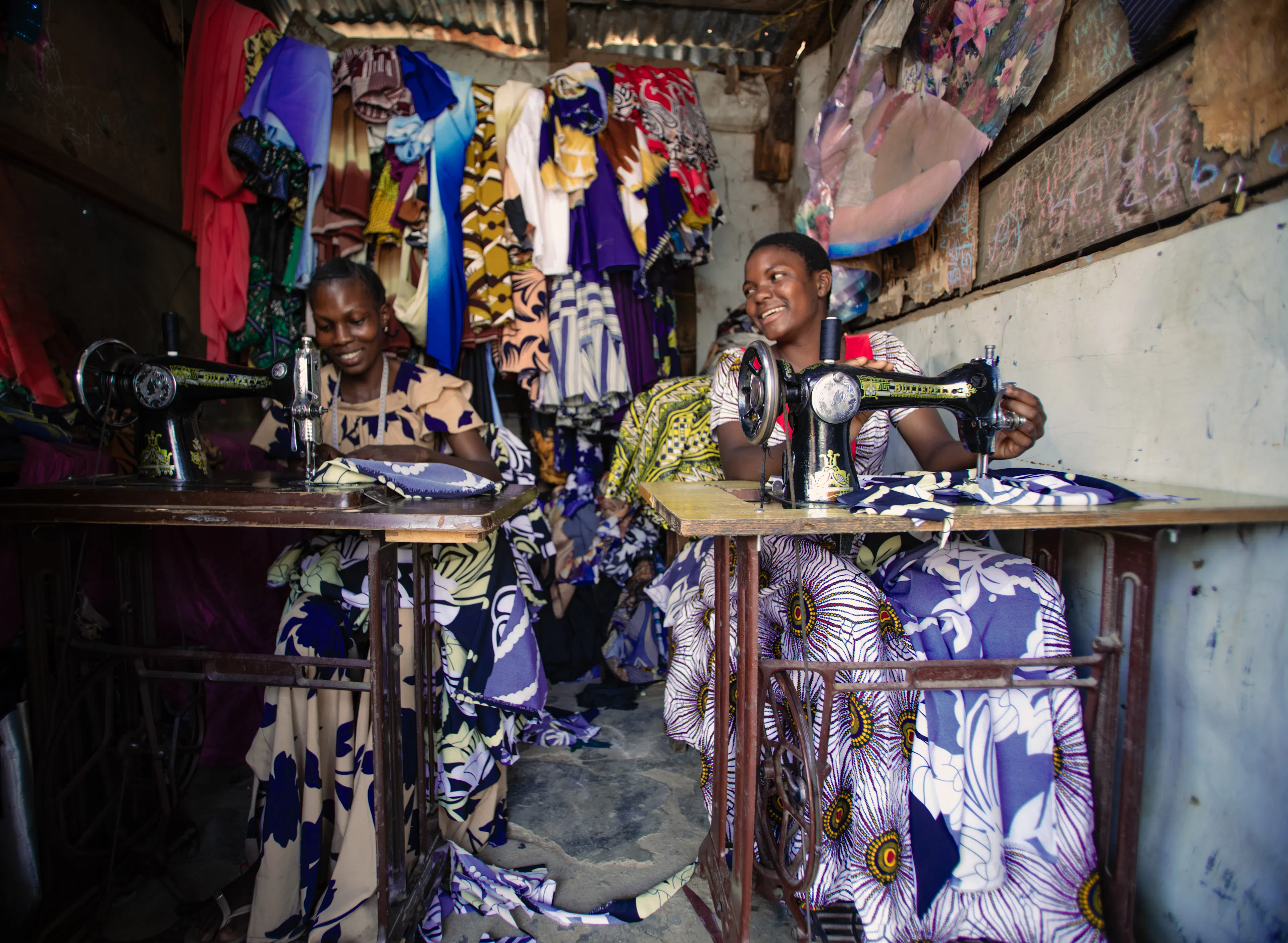 On 13 August 2025, Antini Mahepa (right), 17, works as a sewing apprentice, alongside her mentor Ester Matata Ngoma, 25, in a local market located in the Uvinza District of the Kigoma Region in Tanzania. The small stall, lined with colourful fabrics and garments, is a place for learning and growth.