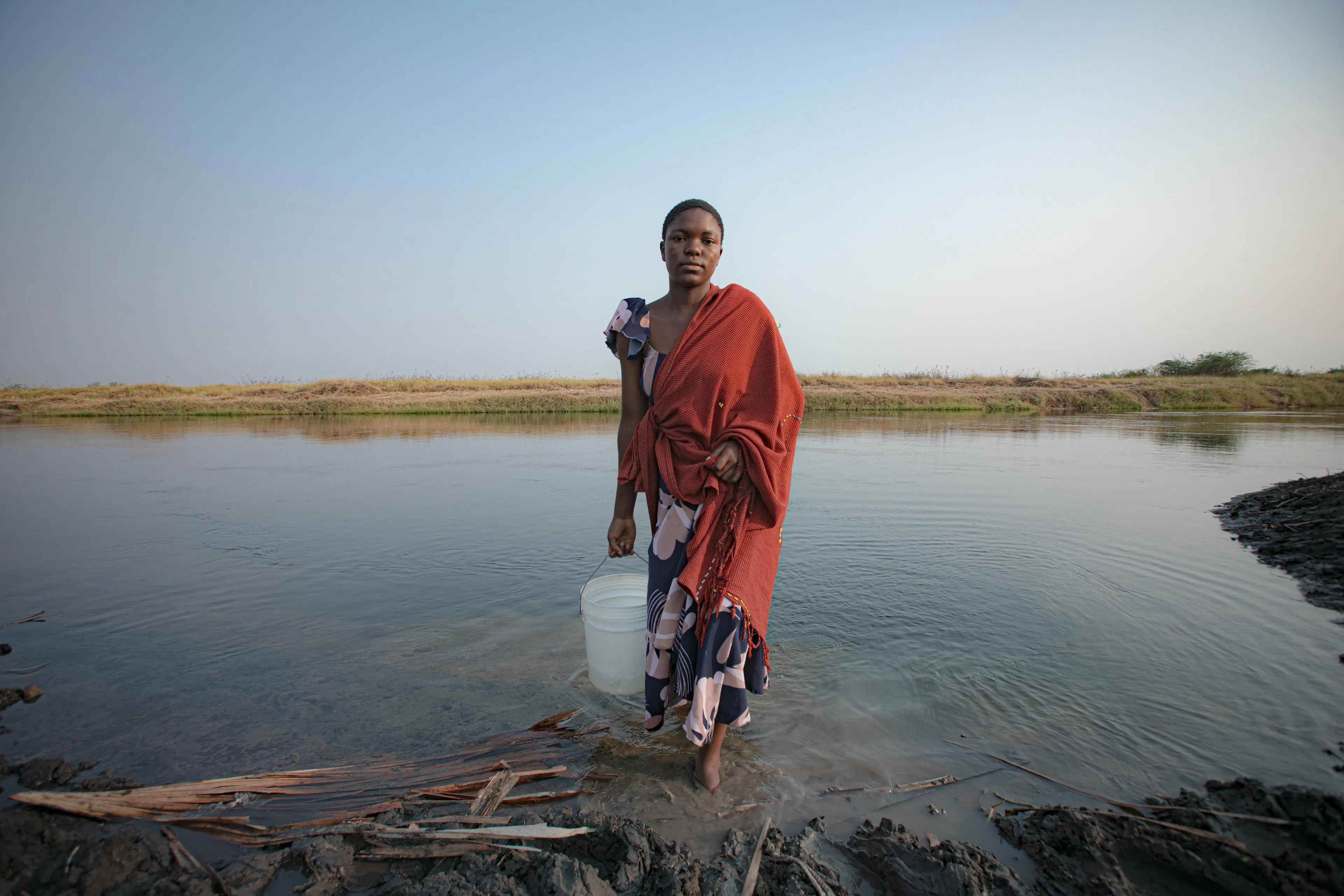 On 13 August 2025, 17-year-old Antini Mahepa fetches water from a nearby lake to bring back for her family's use in Malagalasi Village, located in the Uvinza District of the Kigoma Region in Tanzania.