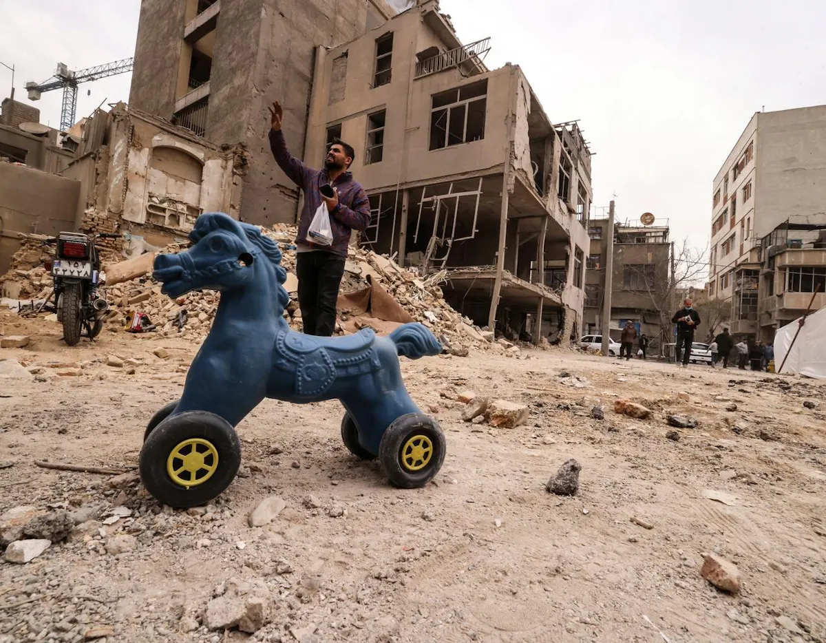 An Iranian man gestures as he stands near destroyed homes following a military strike on the Iranian capital Tehran on 15 March 2026. 