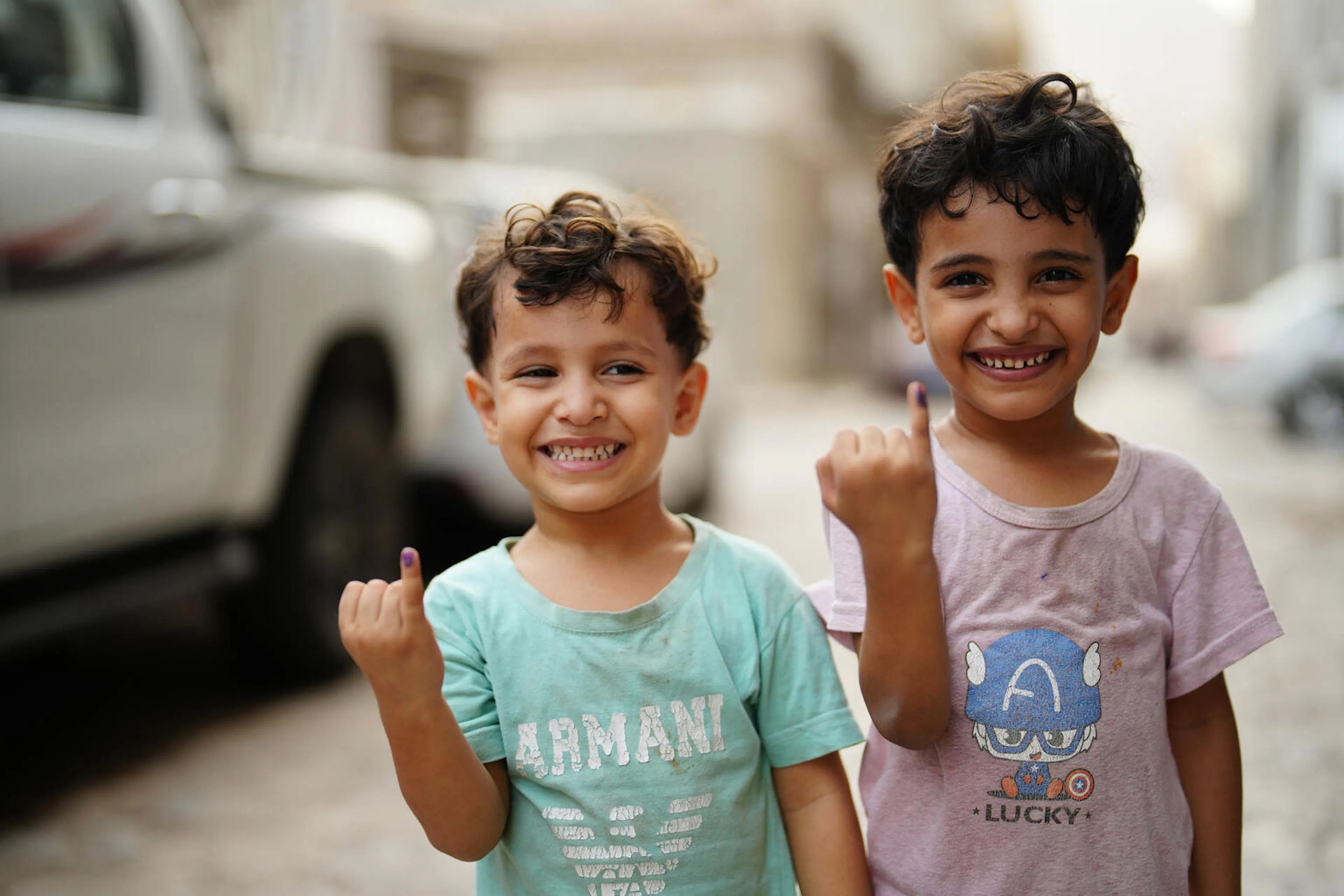 Children smile and raise their marked fingers after receiving the polio vaccine at their neighborhood in Aden, Yemen.