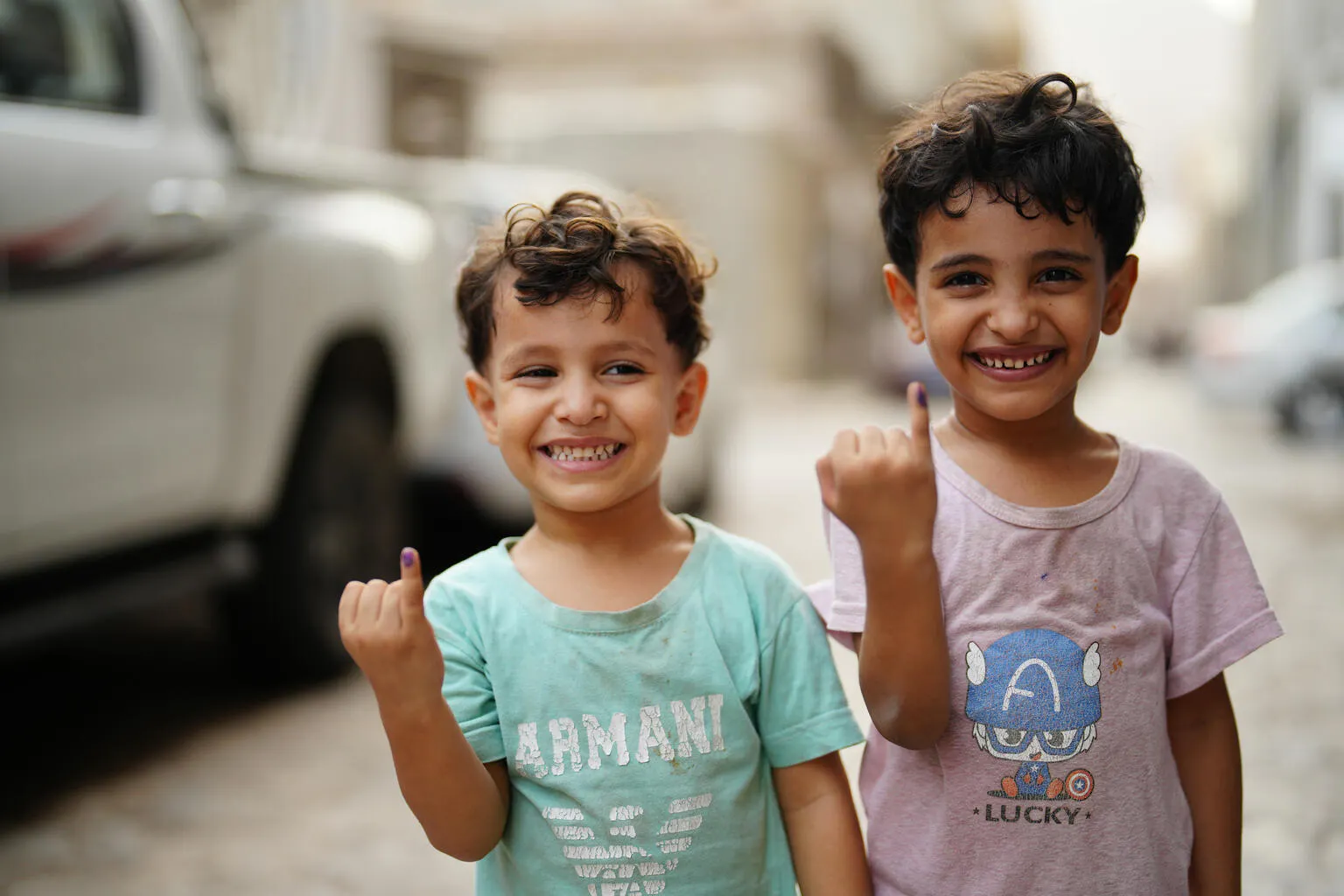 Children smile and raise their marked fingers after receiving the polio vaccine at their neighborhood in Aden, Yemen.