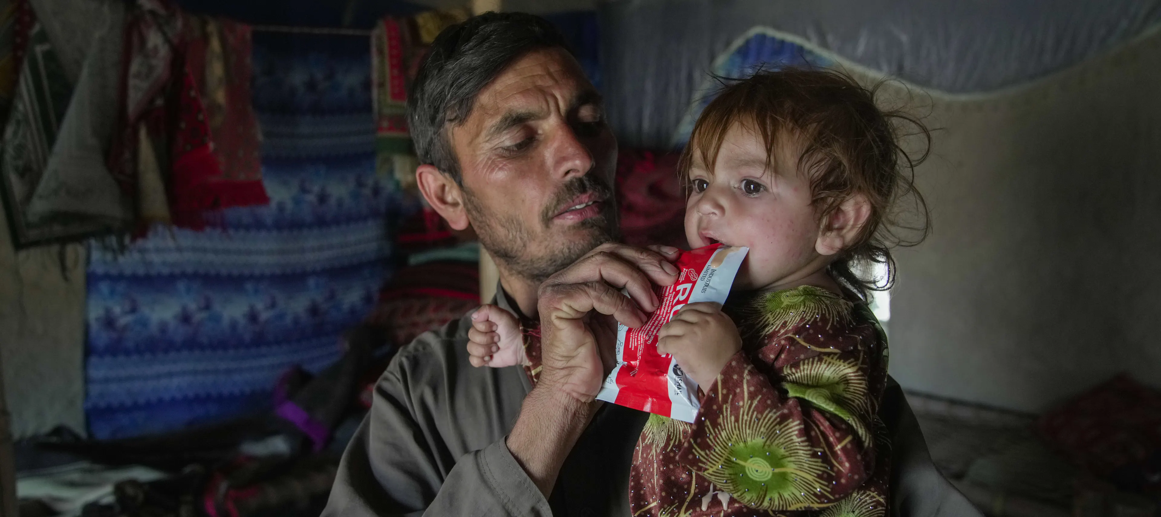 Father feeds child RUTF sachet
