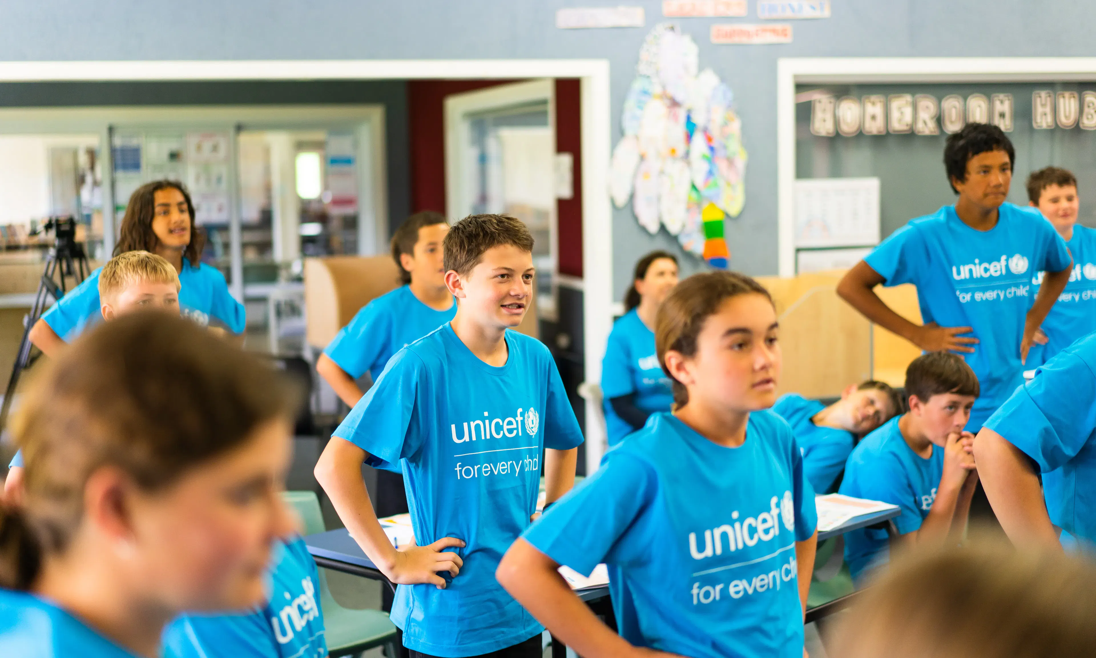 School children at Poipoi School wearing bright blue UNICEF "for every child" t-shirts while standing in a classroom during a 2022 visit.