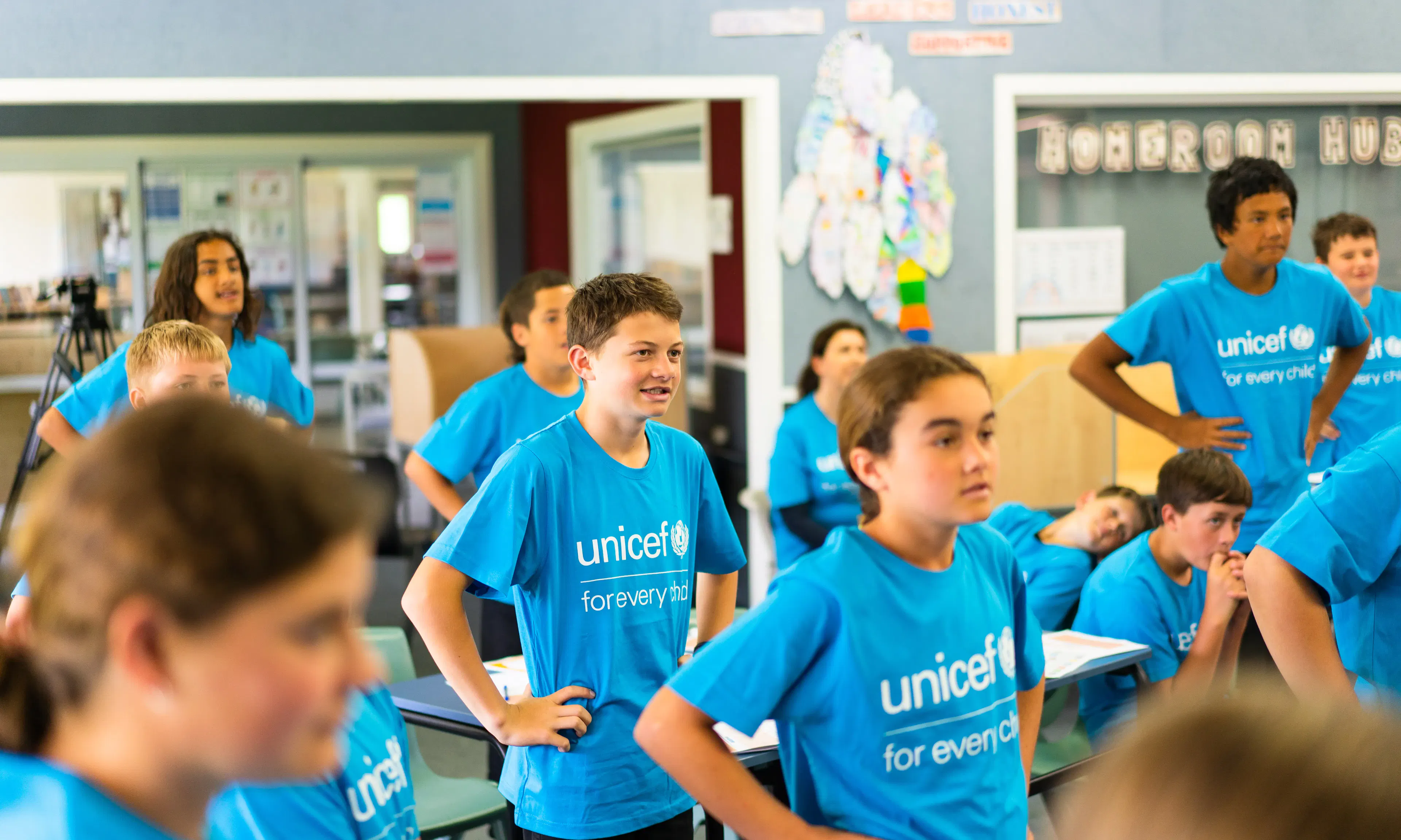 School children at Poipoi School wearing bright blue UNICEF "for every child" t-shirts while standing in a classroom during a 2022 visit.