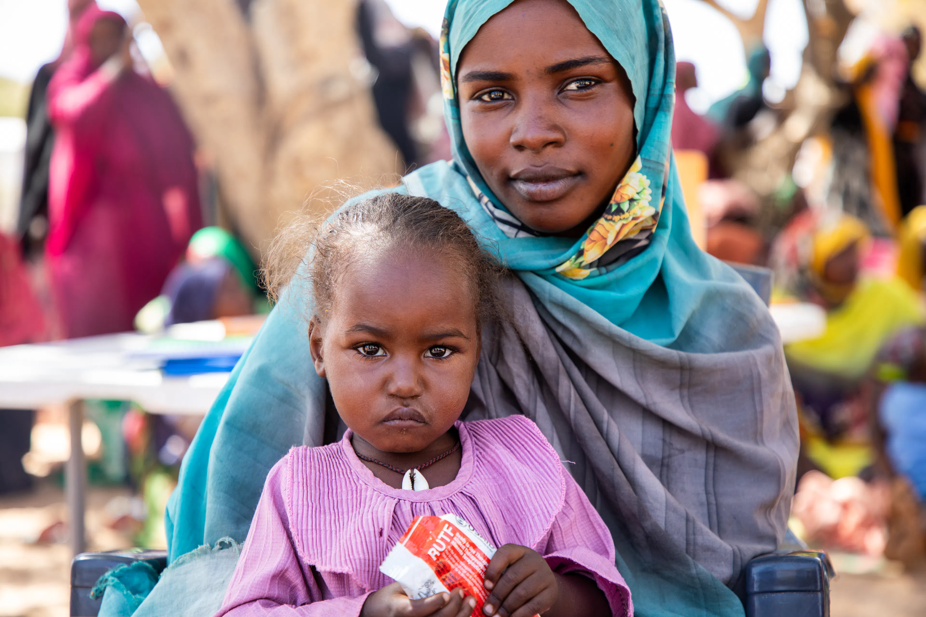 Mother holds child with RUTF sachet
