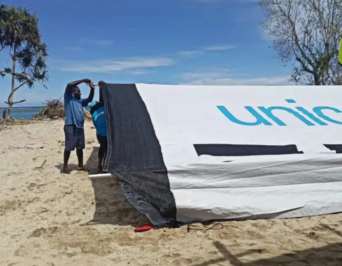 UNICEF staff and partners work together under the heat of the sun to assemble a temporary learning space in Choiseul Province.