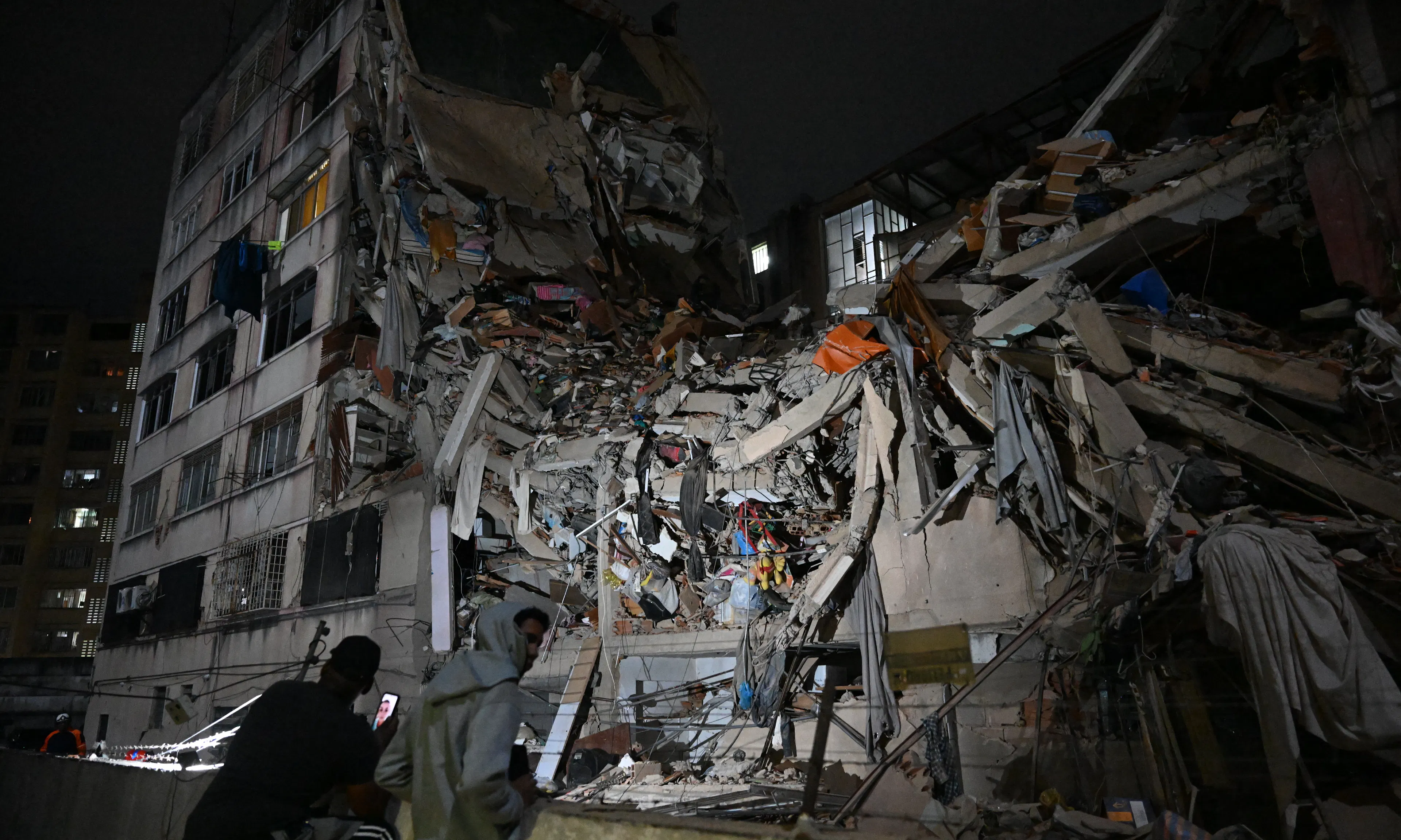 People look at a collapsed building in the Altamira neighbourhood following an earthquake in Caracas on June 24, 2026.