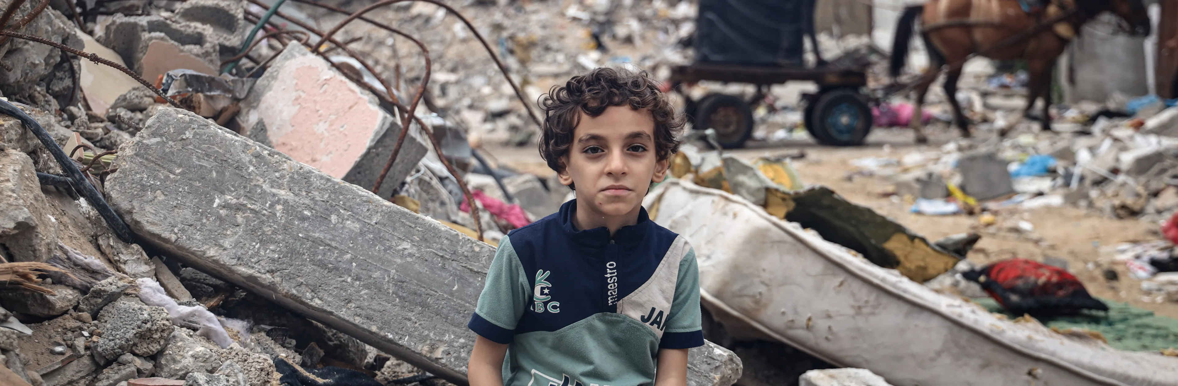 Mohammed Alattar, 8-year-old from Rafah City, sits on the rubble of his family's house, which was bombed in an Israeli airstrike.