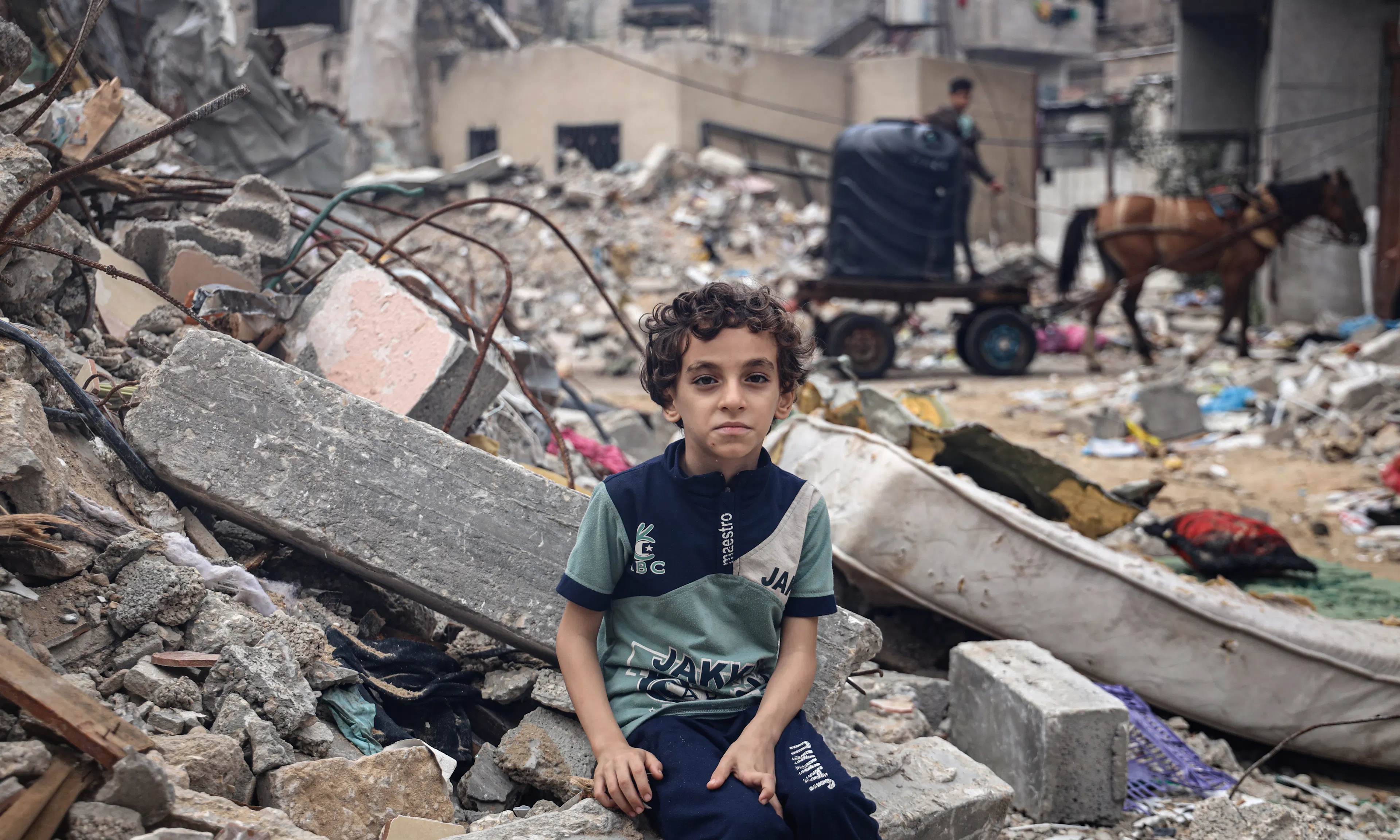 Mohammed Alattar, 8-year-old from Rafah City, sits on the rubble of his family's house, which was bombed in an Israeli airstrike.