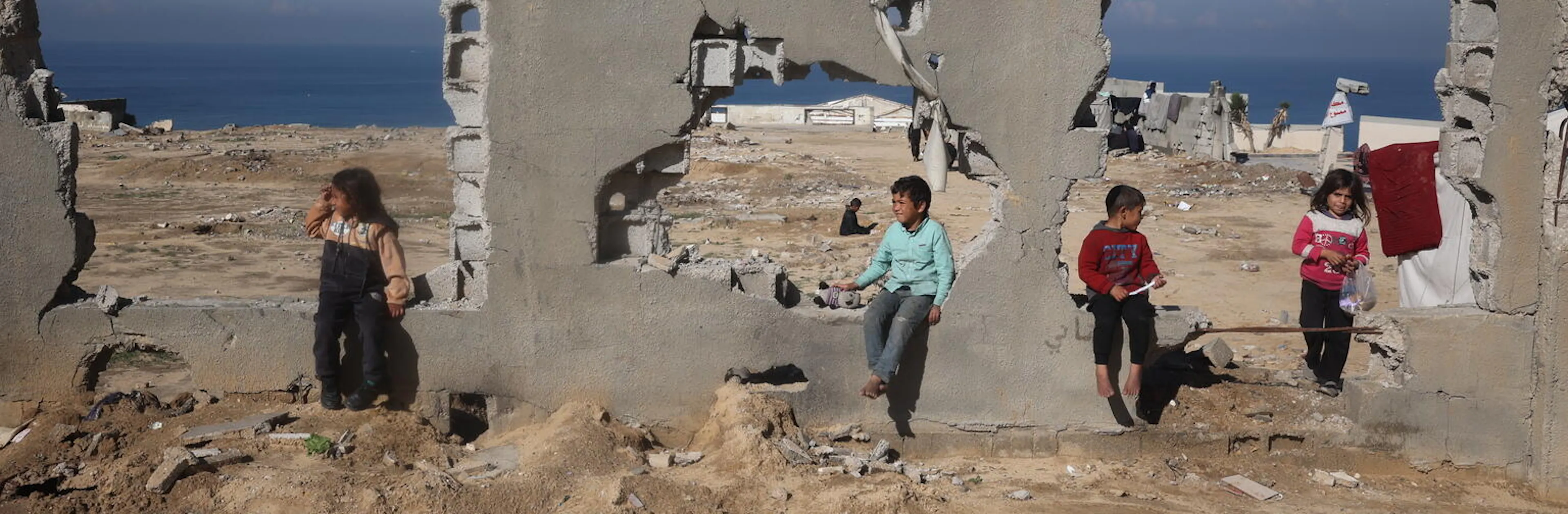 Children sit in the ruins of a destroyed building in Al Nuseirat, in central Gaza Strip