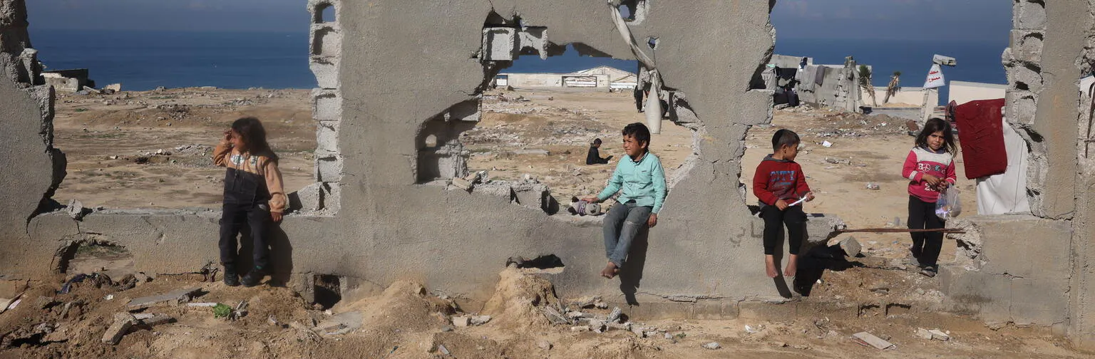 Children sit in the ruins of a destroyed building in Al Nuseirat, in central Gaza Strip
