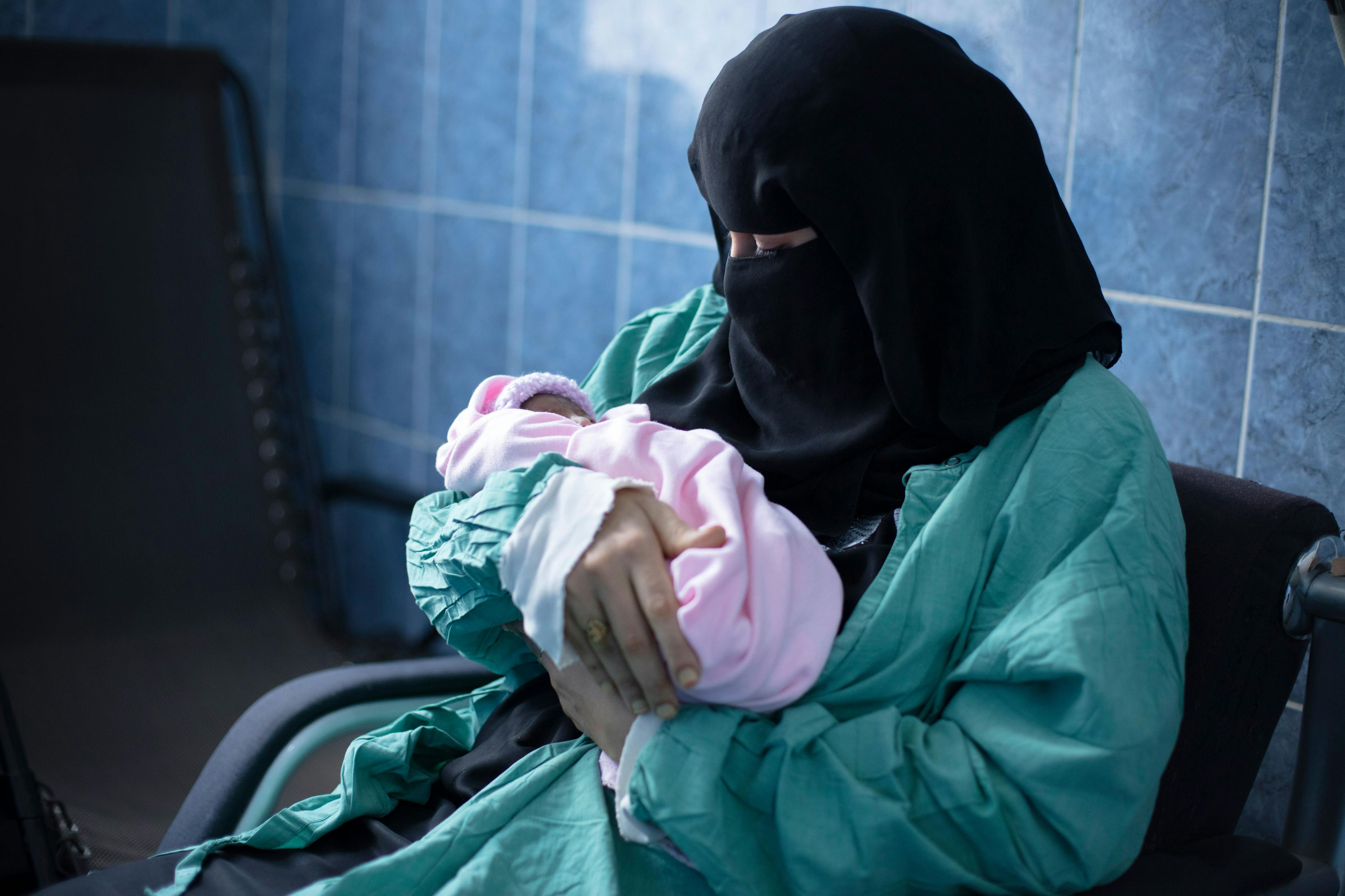 Iftikhar cradles her son, Hassan, in the neonatal intensive care unit