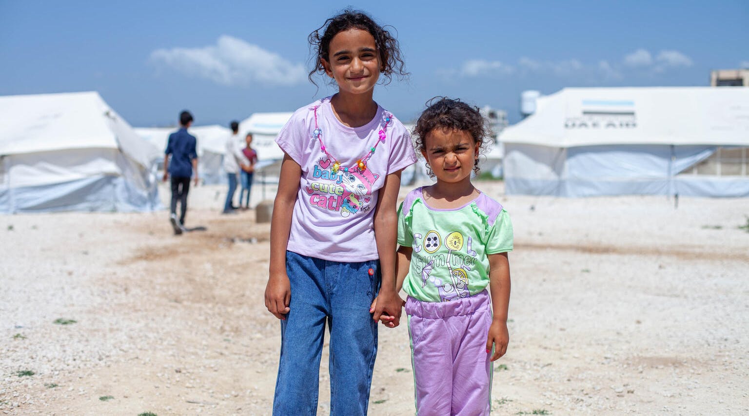 Türkiye-Syria Earthquake Emergency, Two girls in new clothes, distributed by UNICEF at a camp sheltering earthquake-displaced families in Jableh city, Lattakia, Syria.