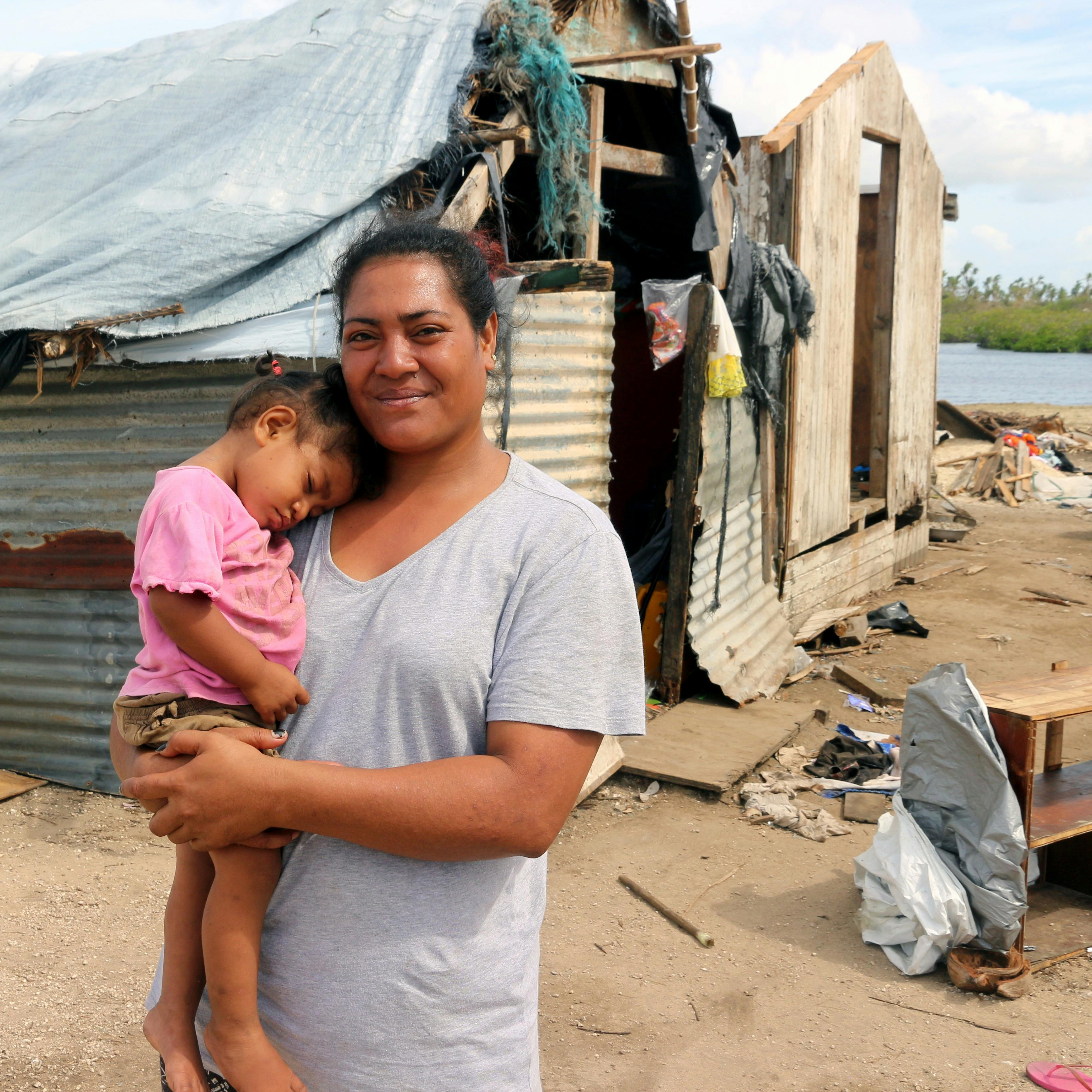 A mother and her child standing outside their home that was destroyed in a cyclone that tore through Vanuatu