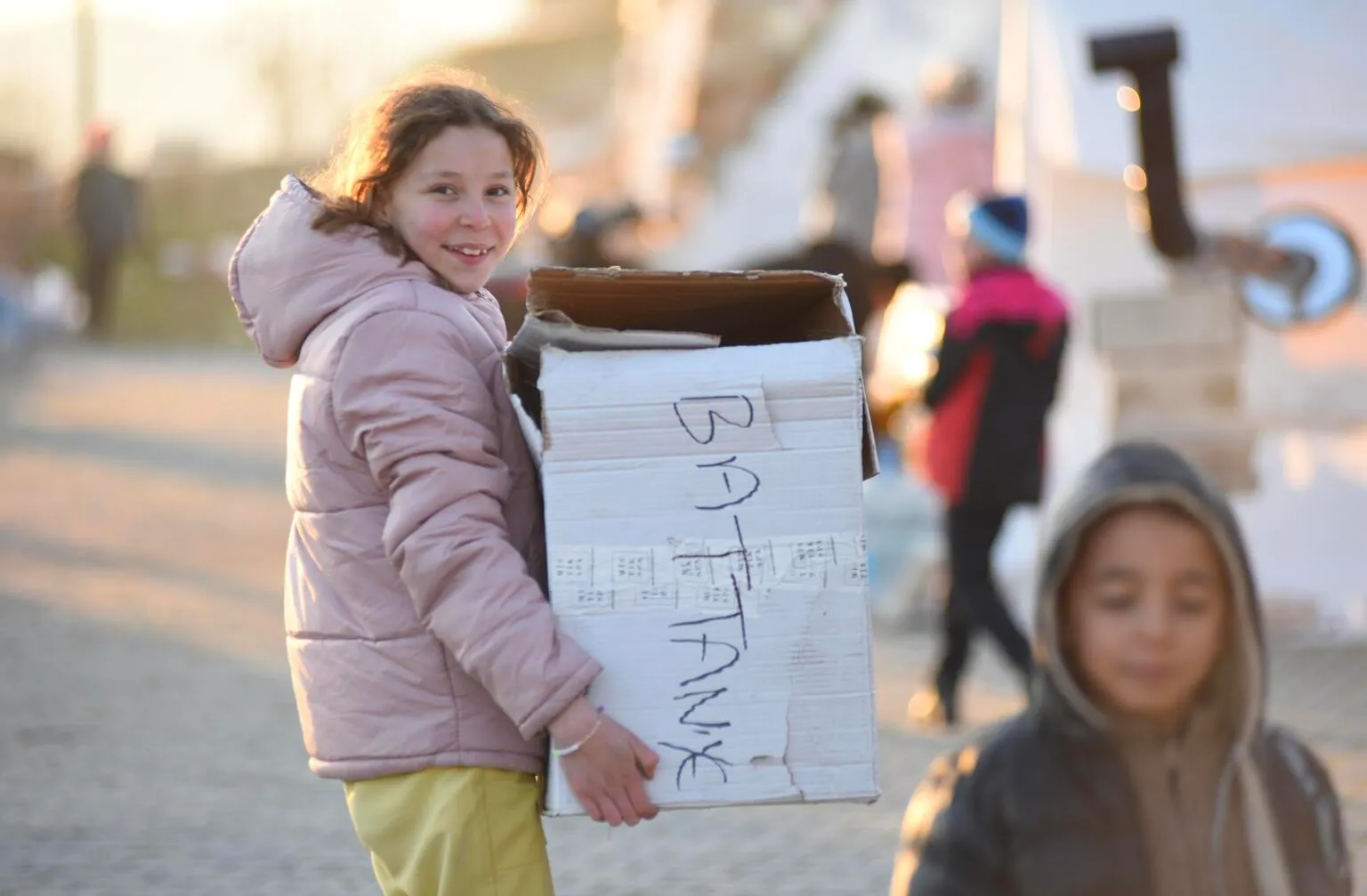 A girl is happy to have her blanket in the box at the temporary shelter set up for the survivors of the 7.7 magnitude earthquake in Kahramanmaraş, Türkiye.